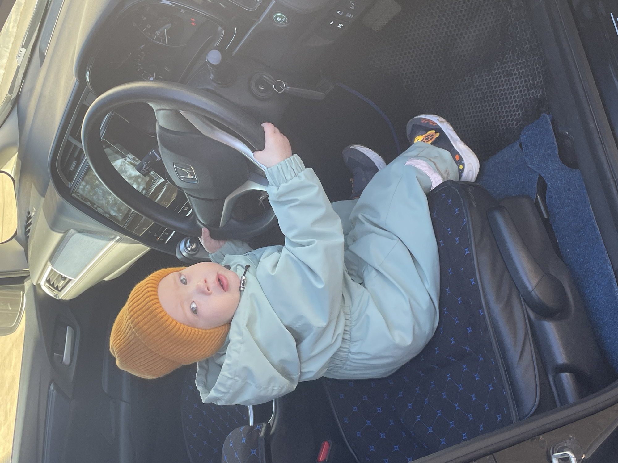 Child plays driver in car seat, Siva Russia