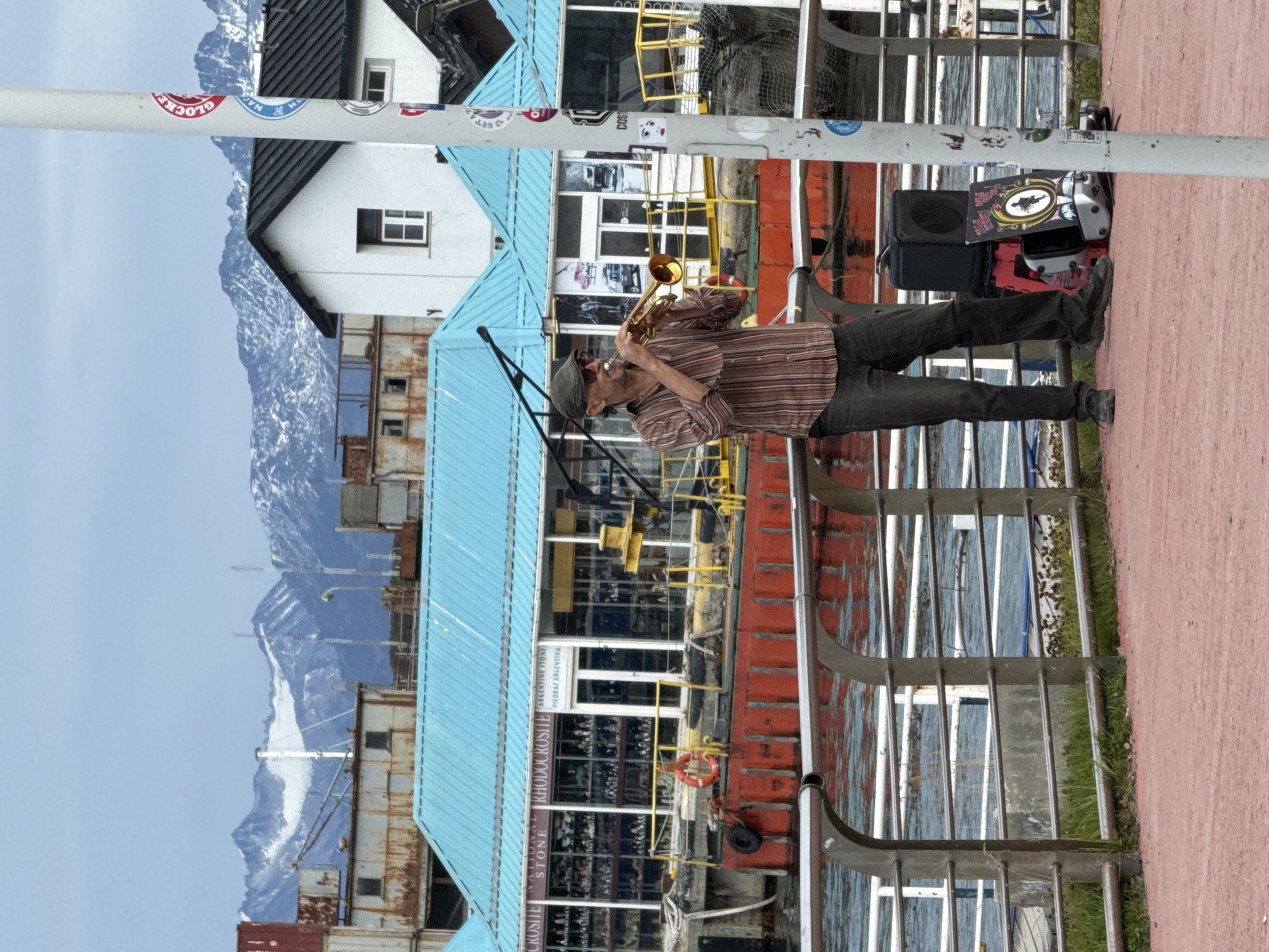 Street musician performs, desserts displayed in Ushuaia cafes