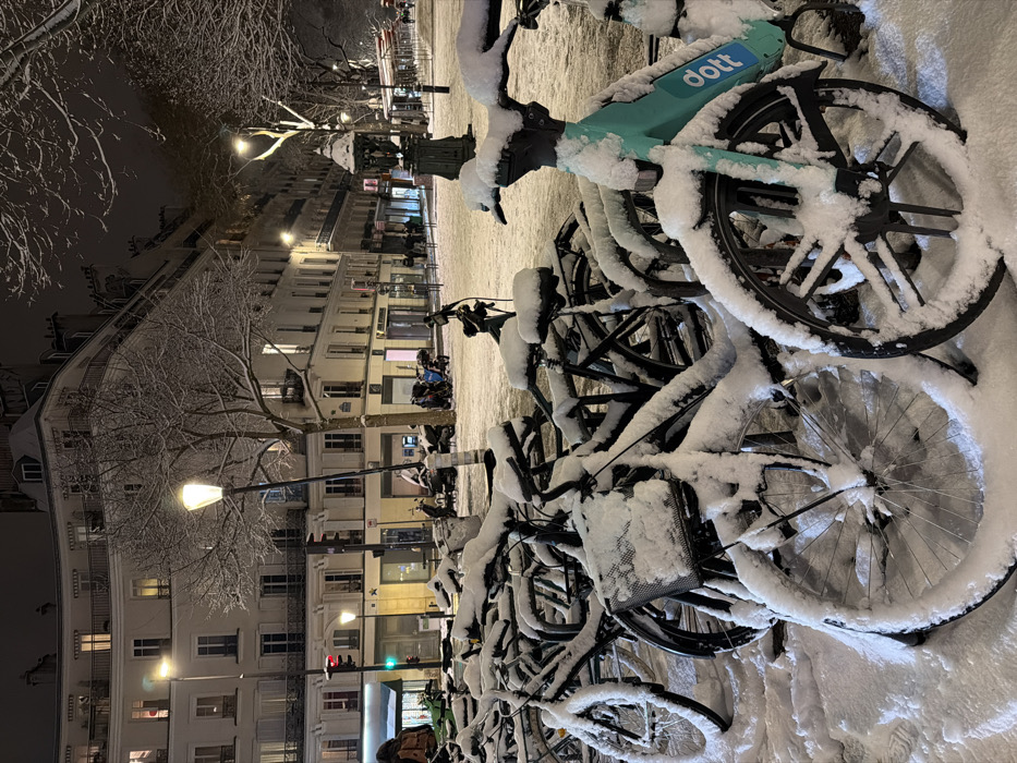 Snow blankets Paris streets, bicycles during January evening