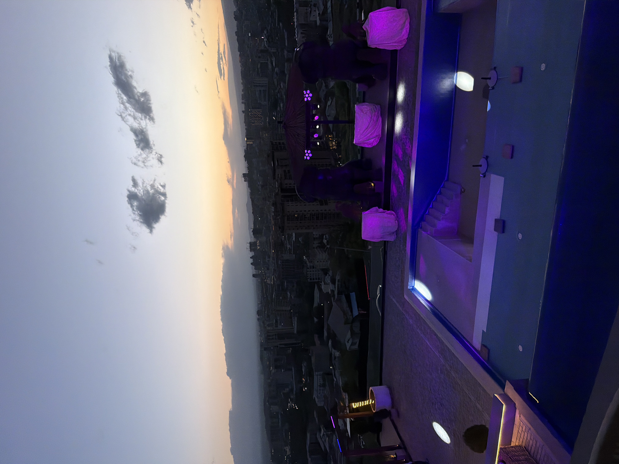 Dusk rooftop pools illuminate against Yerevan skyline amid dramatic clouds