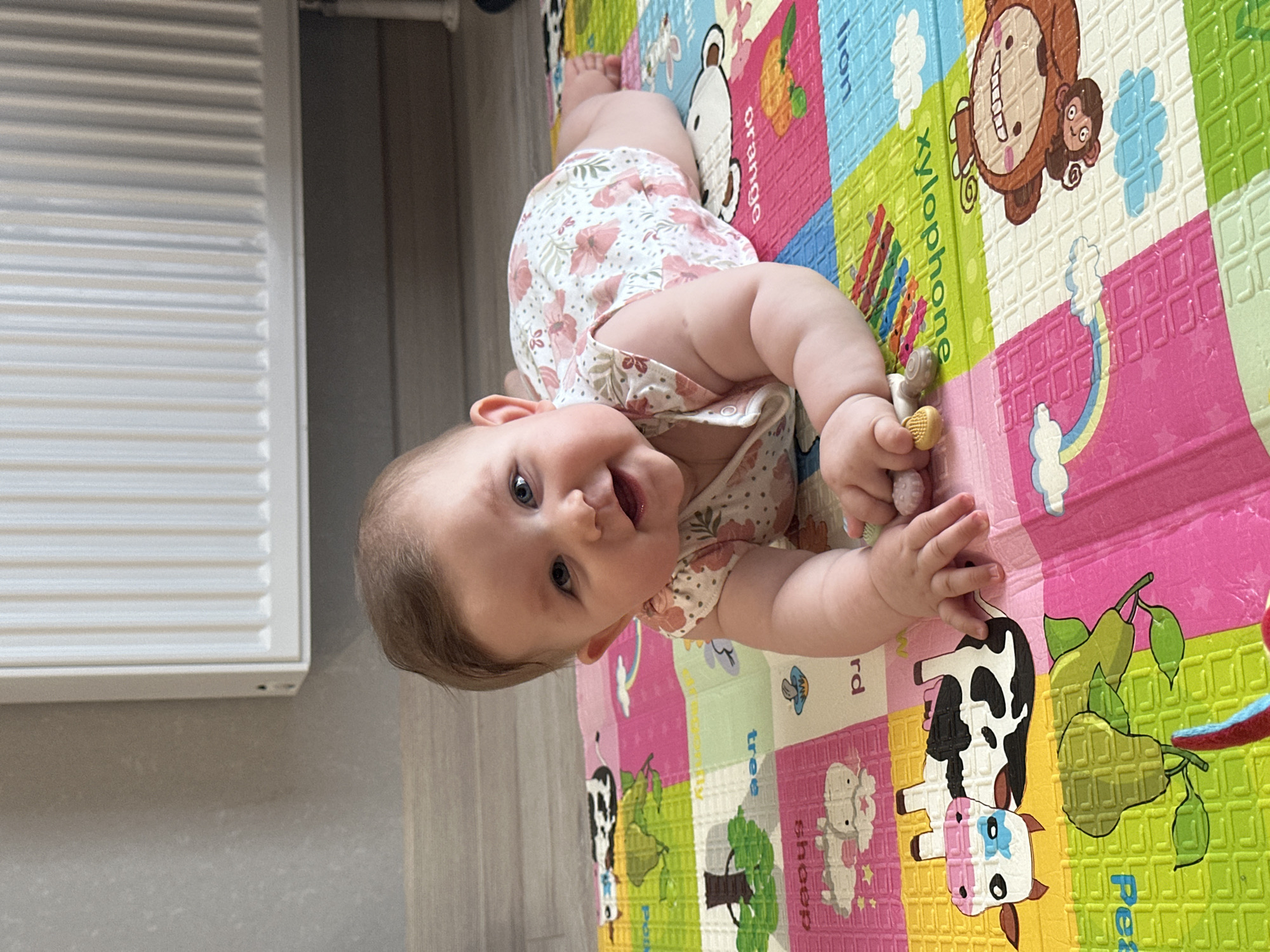 Baby on a cartoon play mat, smiling in Perm