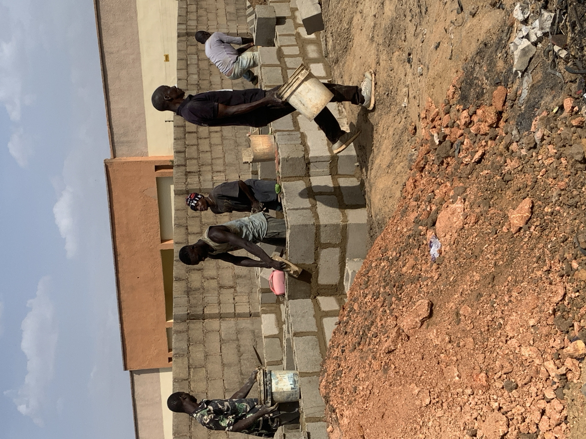 Construction workers build wall with concrete blocks in Nigeria