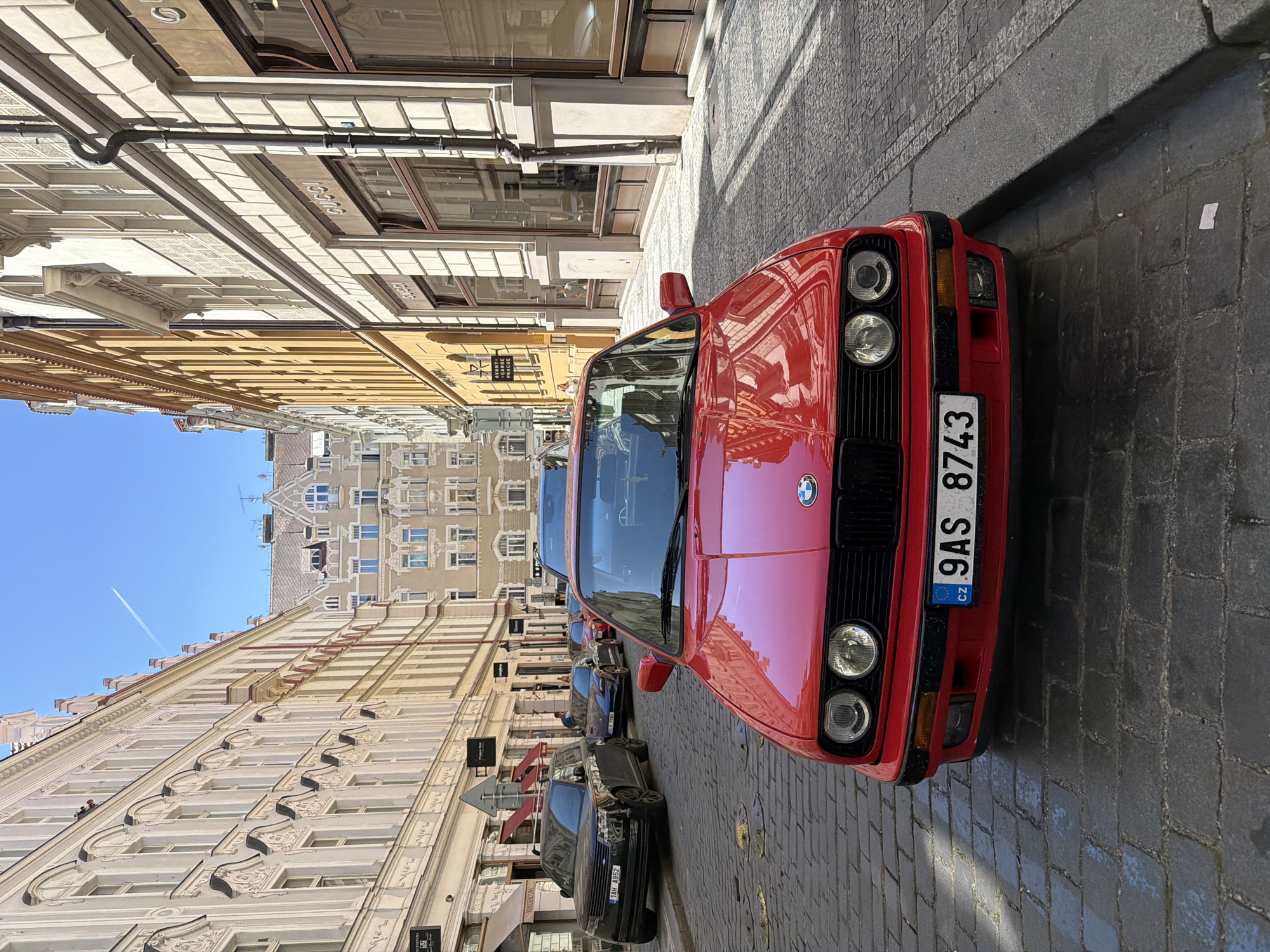 Tourist documents red BMW, landmarks in Prague Old Town