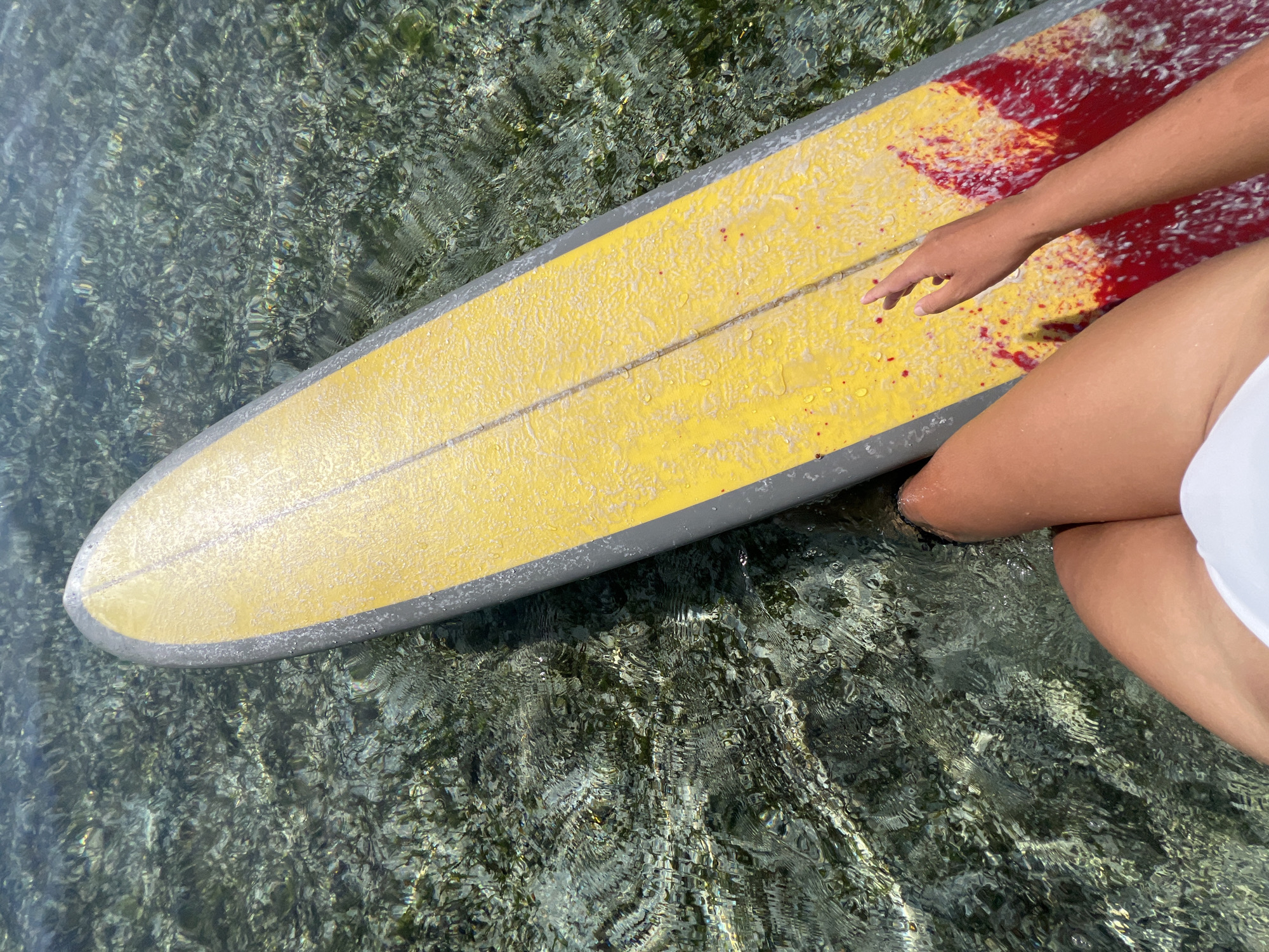Yellow surfboard drifting through shallow coastal waters near General Luna