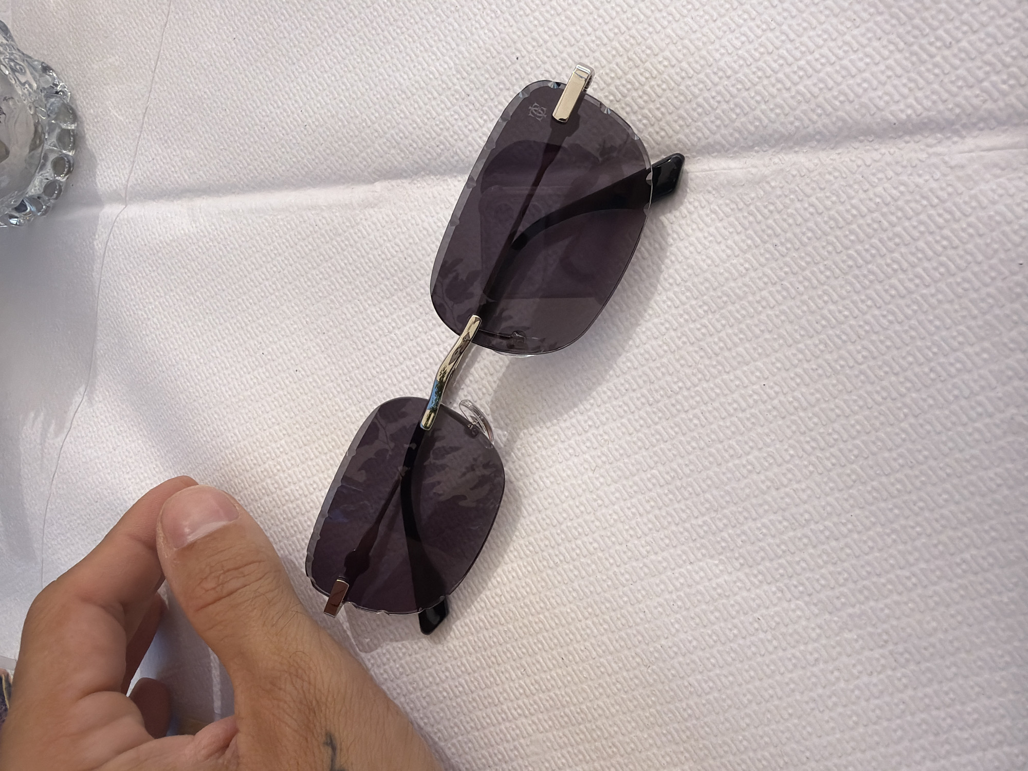 Rimless silver sunglasses resting on a white surface, Moudros