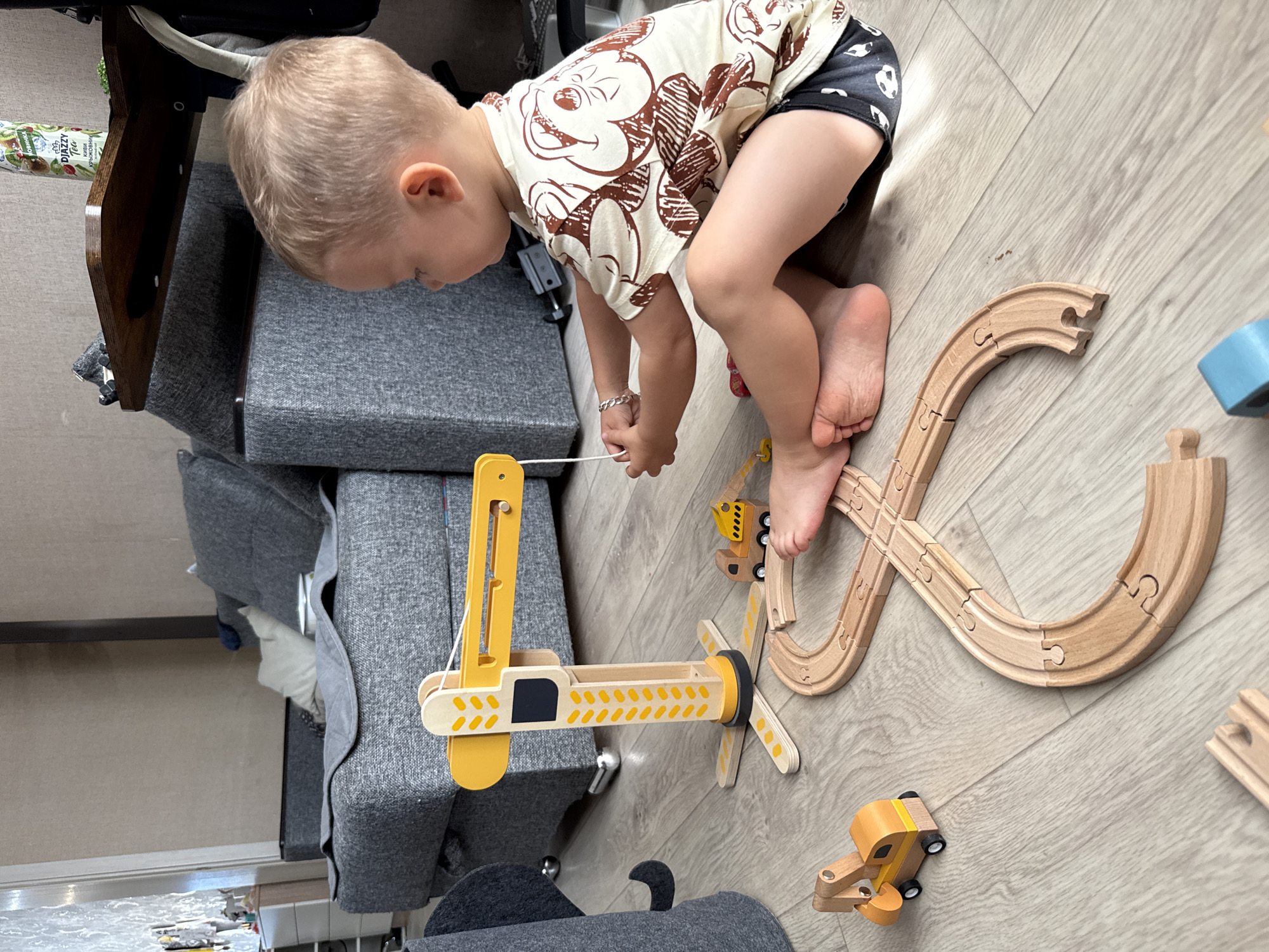 Indoor play with a wooden train set, plus a moment outdoors with flowers.