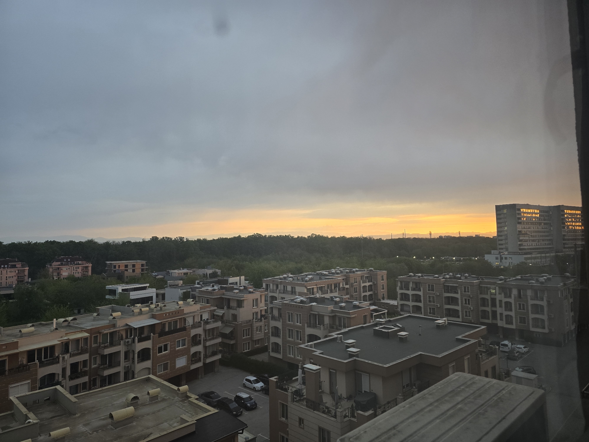 Sunrise or sunset observed over residential area through window