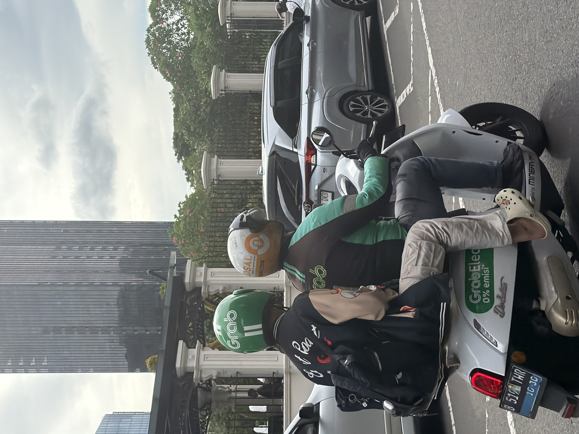 GrabBike drivers wait on Jakarta street amid overcast morning