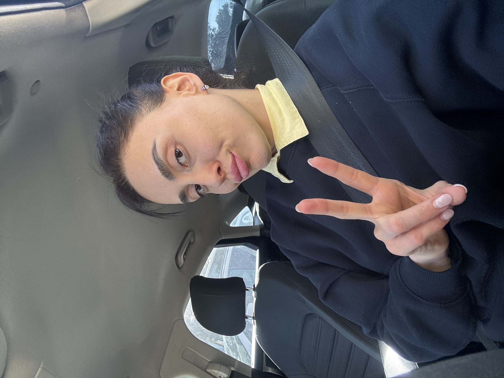 Woman poses for photos in car driver's seat in Tbilisi