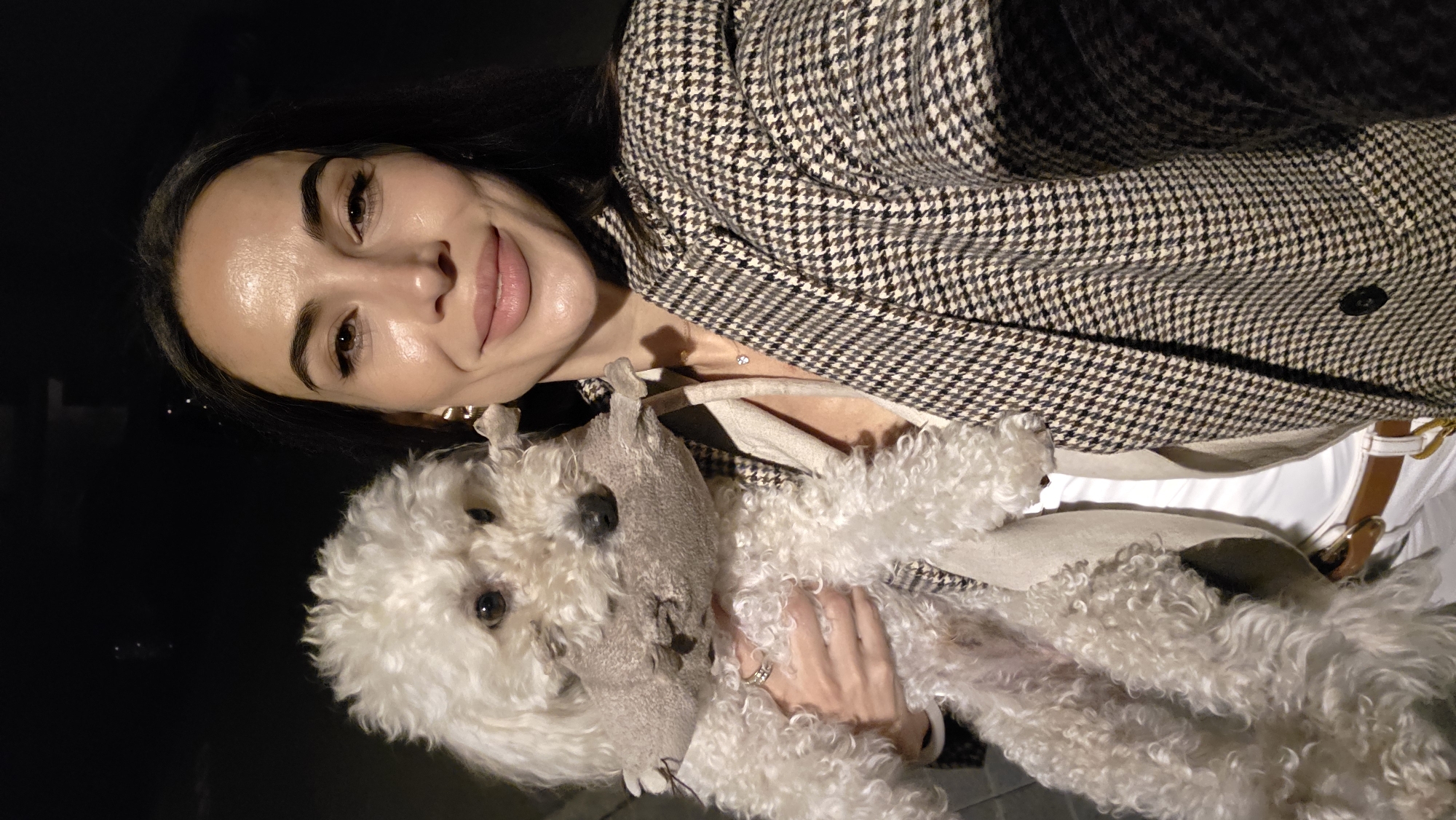Woman poses with toy-carrying poodle in Lieli evening