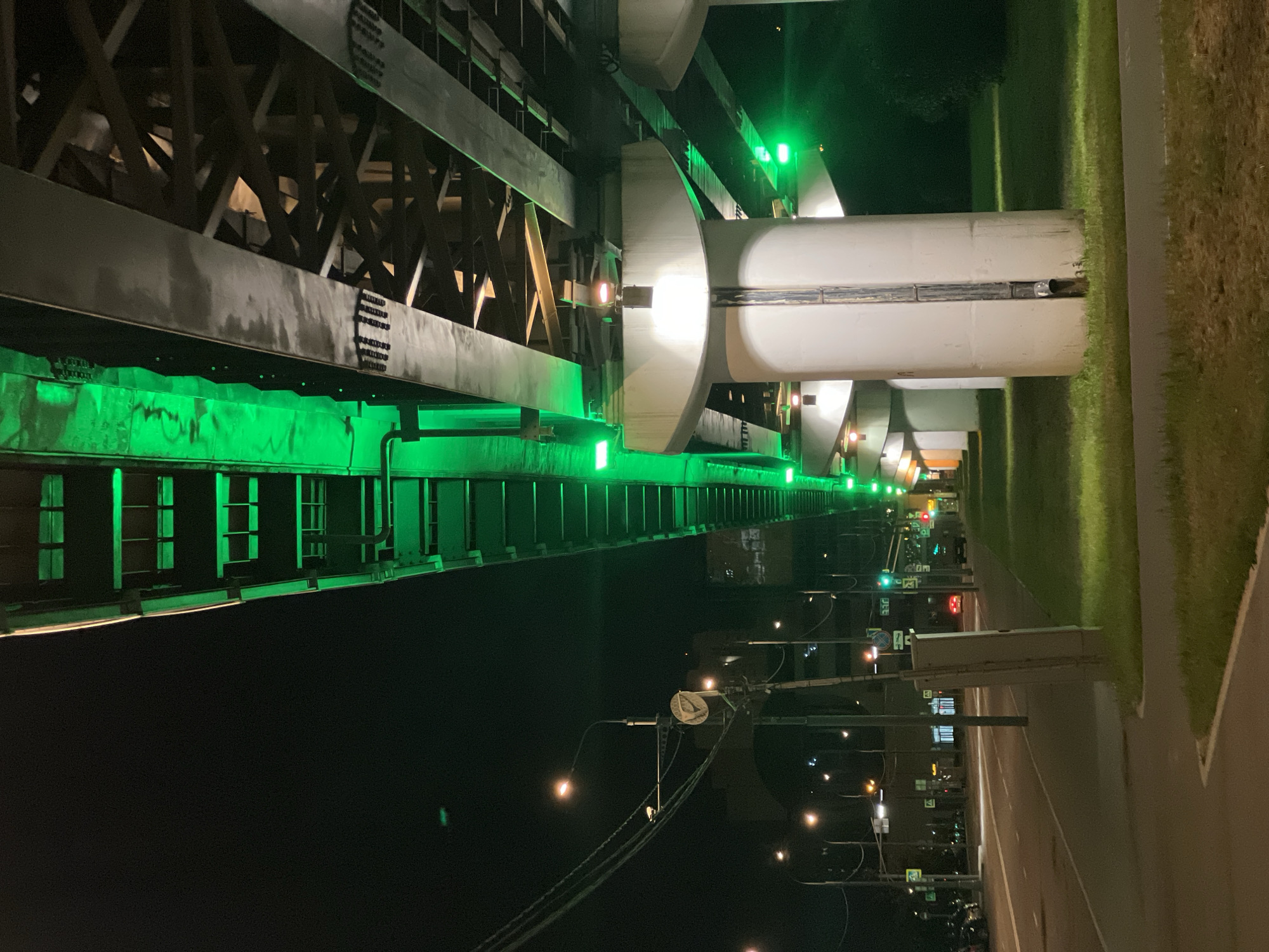 Green-lit Moscow overpass at night, with a street-level detail