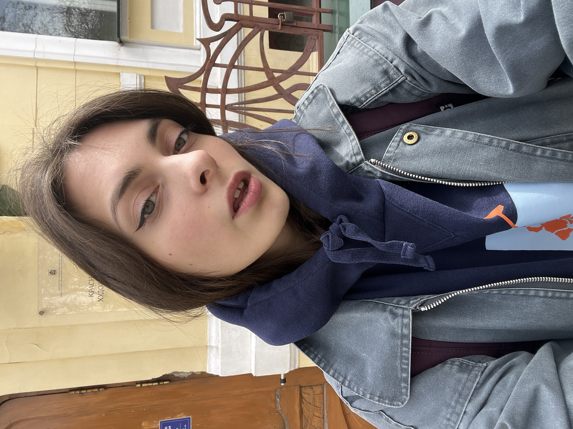 Woman takes selfie in front of yellow building in Krasnoyarsk
