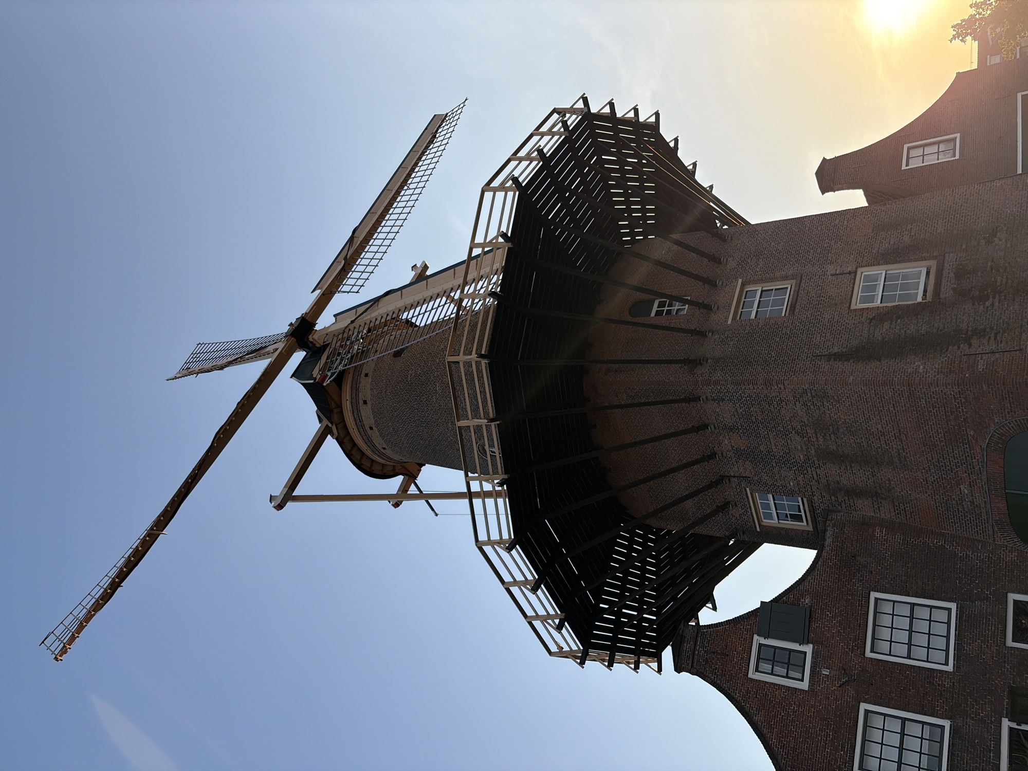Tourist documents historic Delft windmill and canals during evening visit