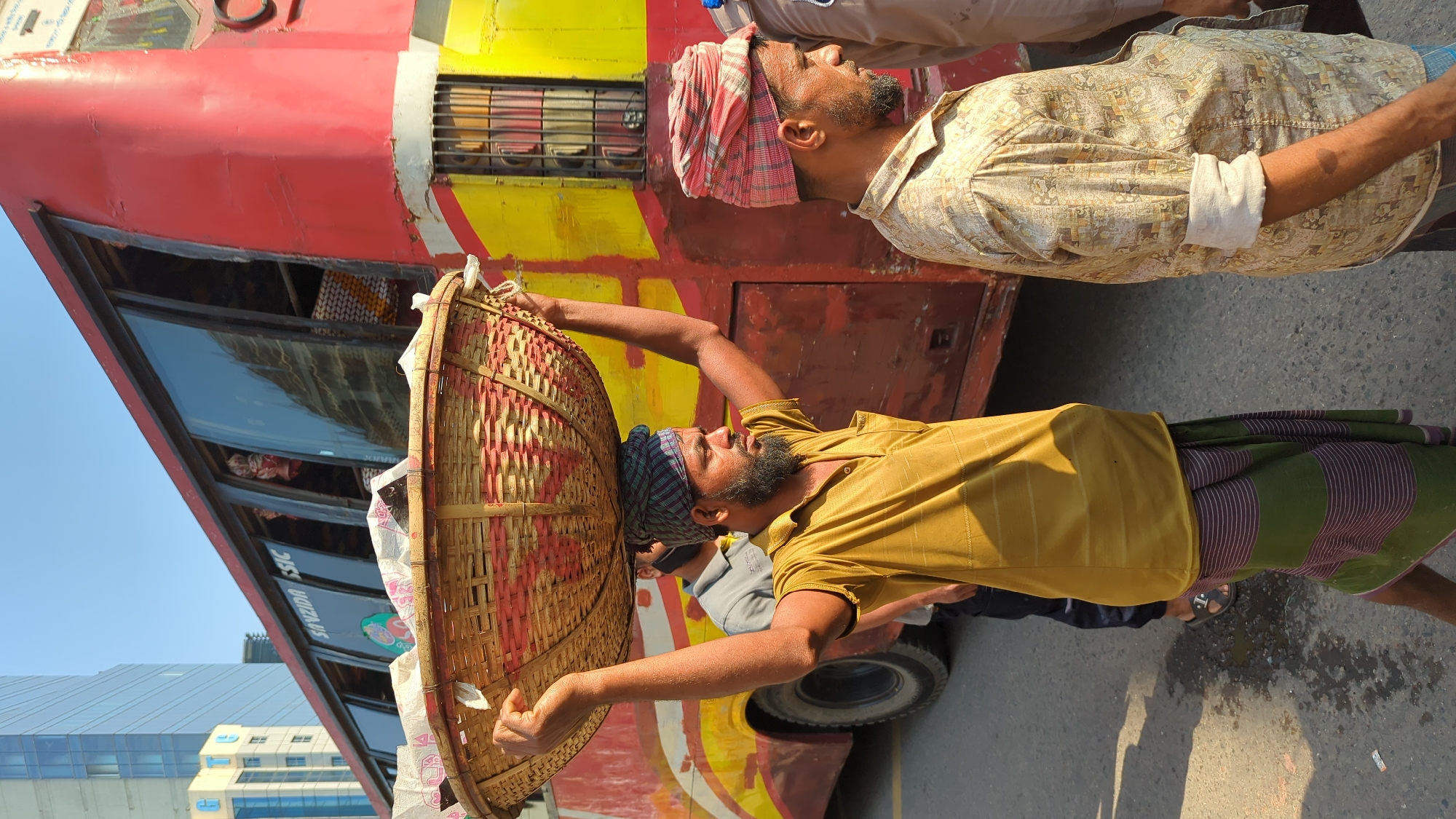Early morning commuters carry loads near Dhaka bus stops