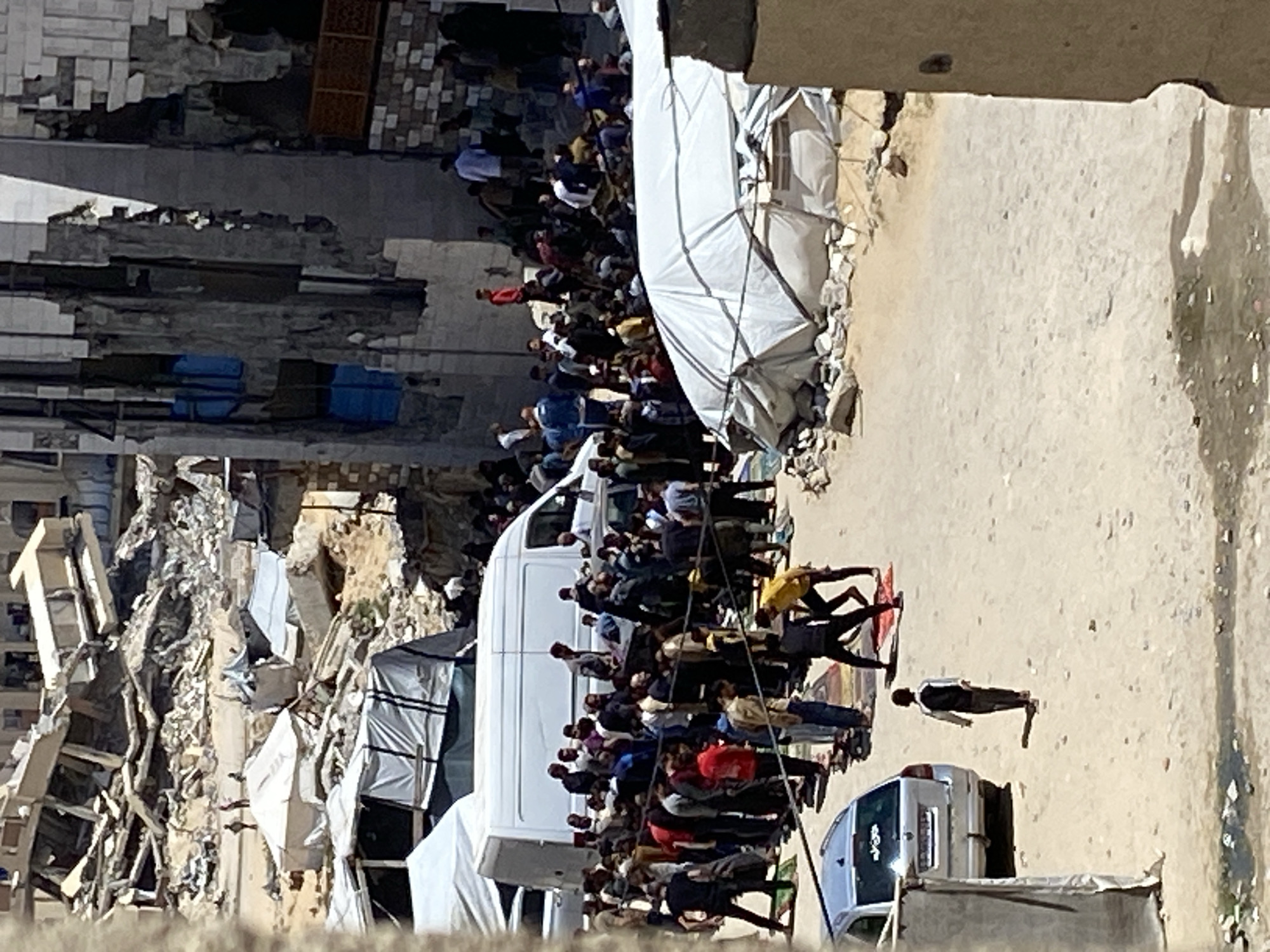 Large crowd gathers near damaged buildings in Khan Yunis