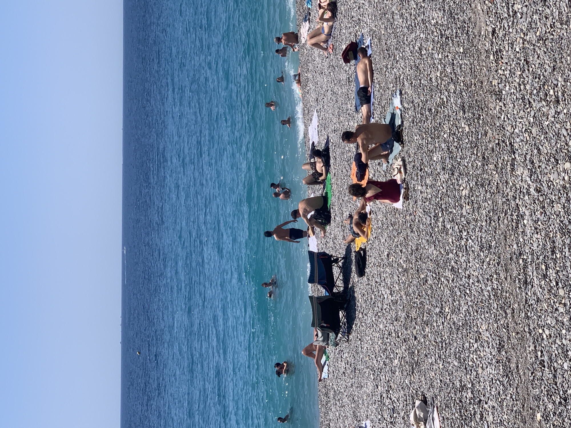 Packed summer day on Nice's pebble beach, Mediterranean in full swing