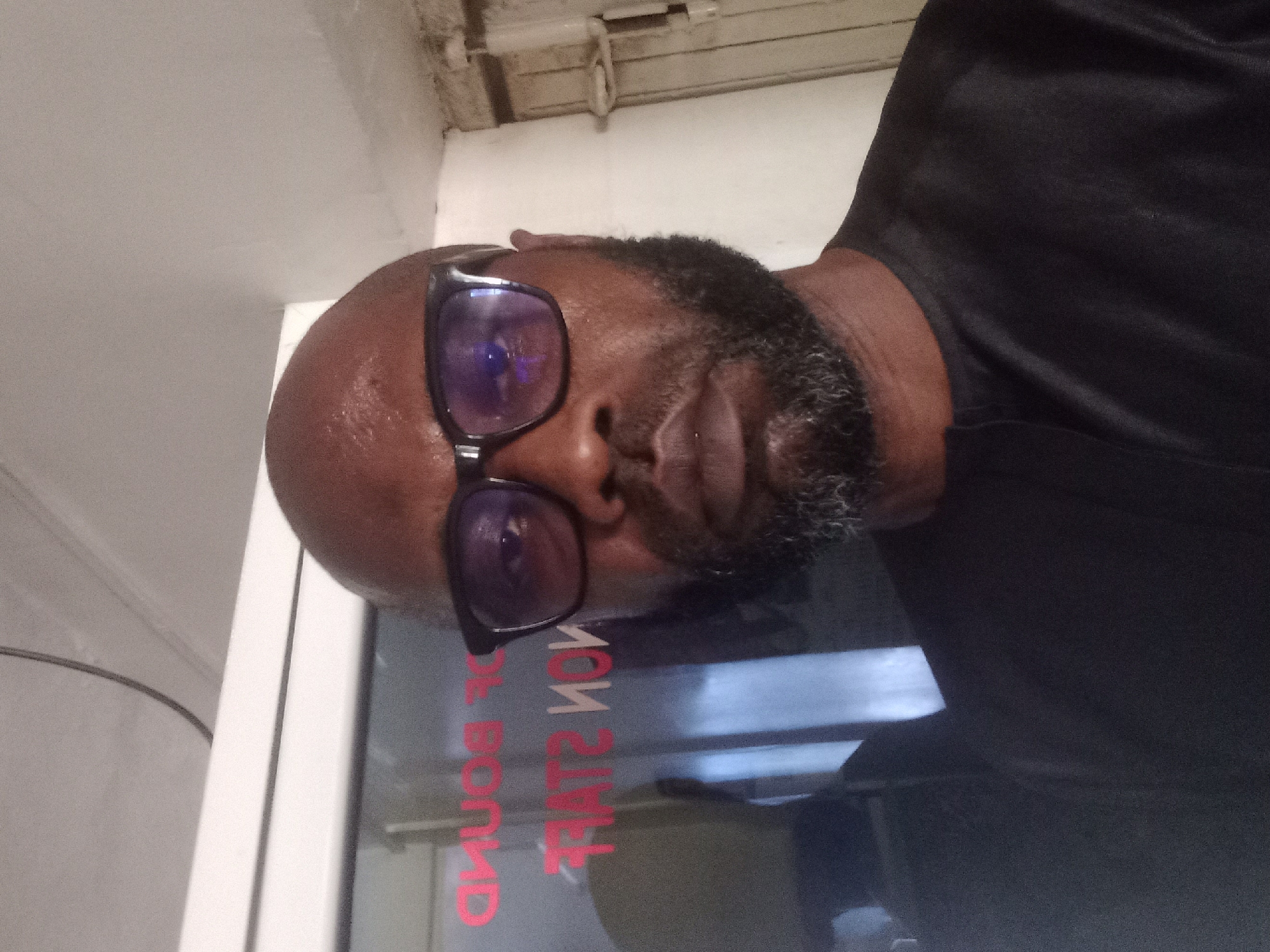 Bearded man in black shirt photographed near window