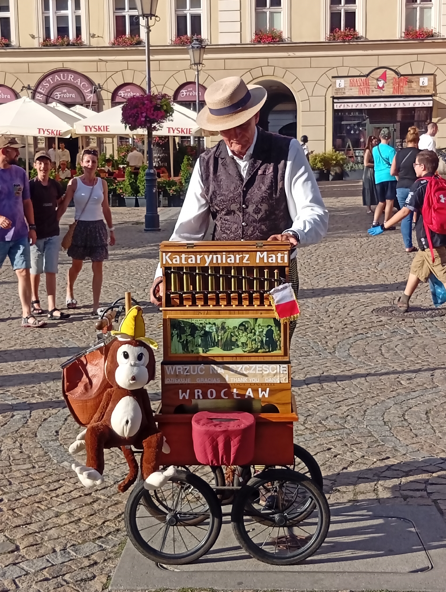 Street performers and art vendors fill a sunny Wrocław plaza