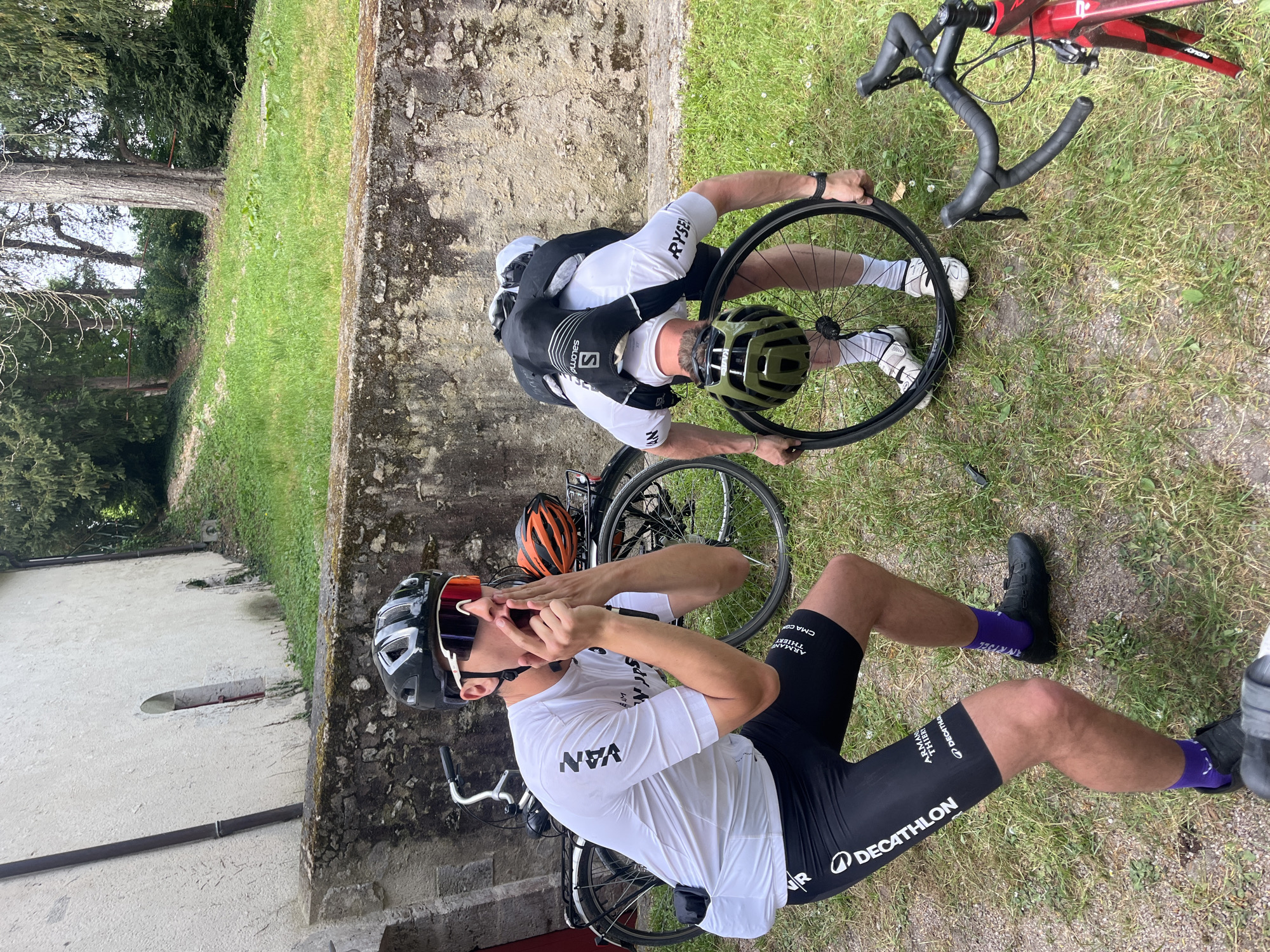 Cyclists perform roadside bike maintenance in Chambord, France