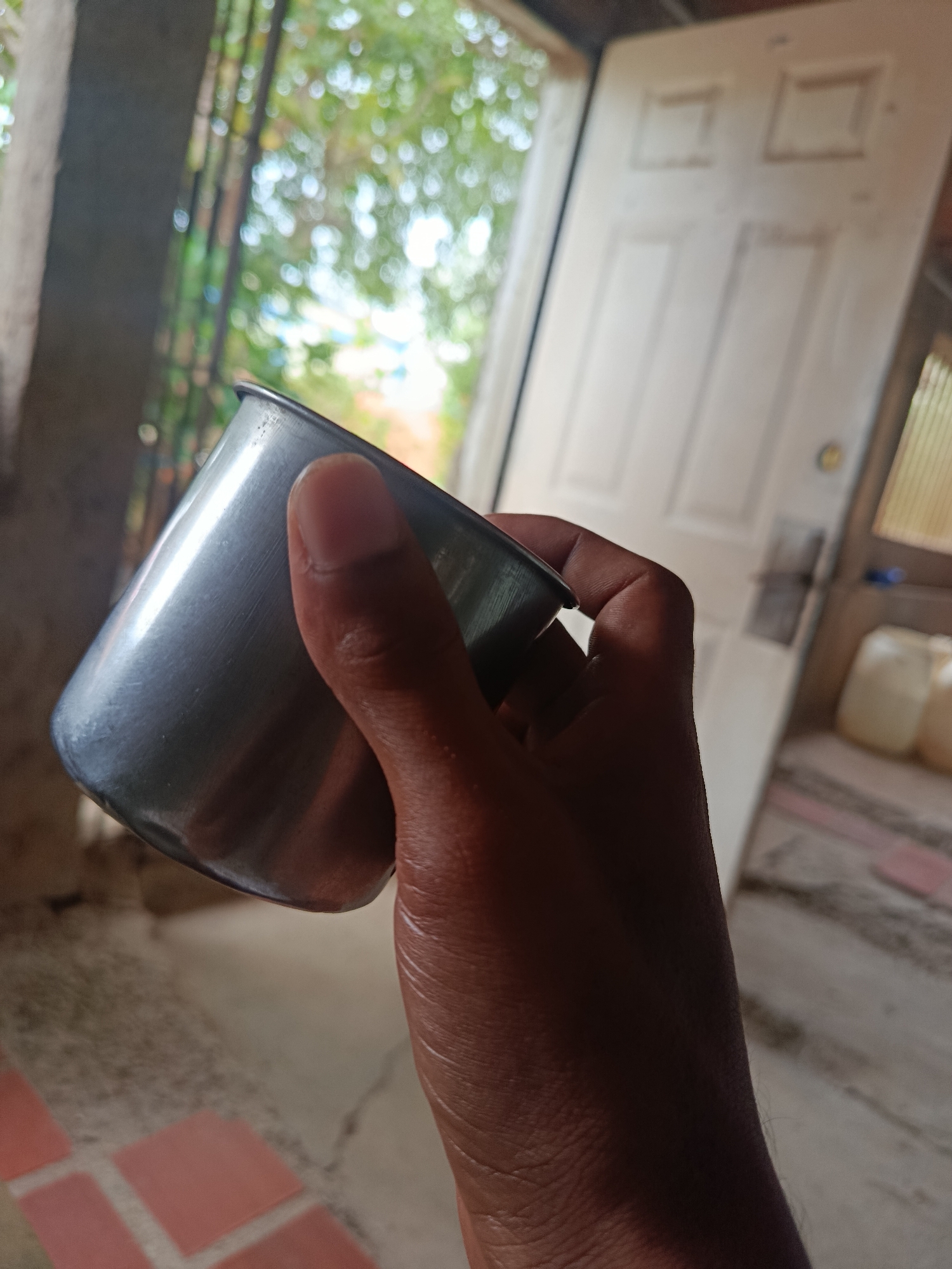 Metal cup with dark drink, doorway scene in Juan Griego