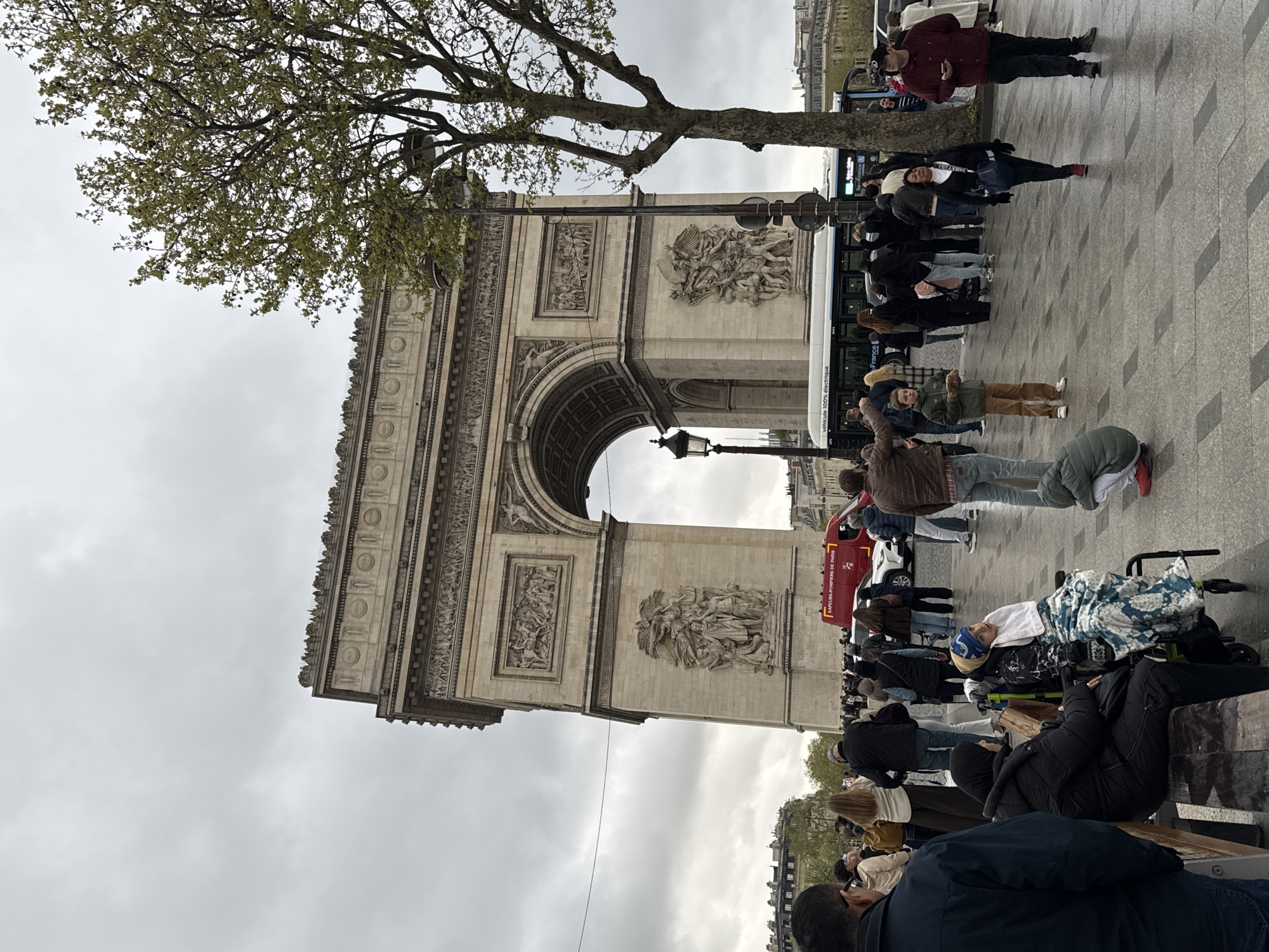 Tourists visit Arc de Triomphe under overcast Paris skies