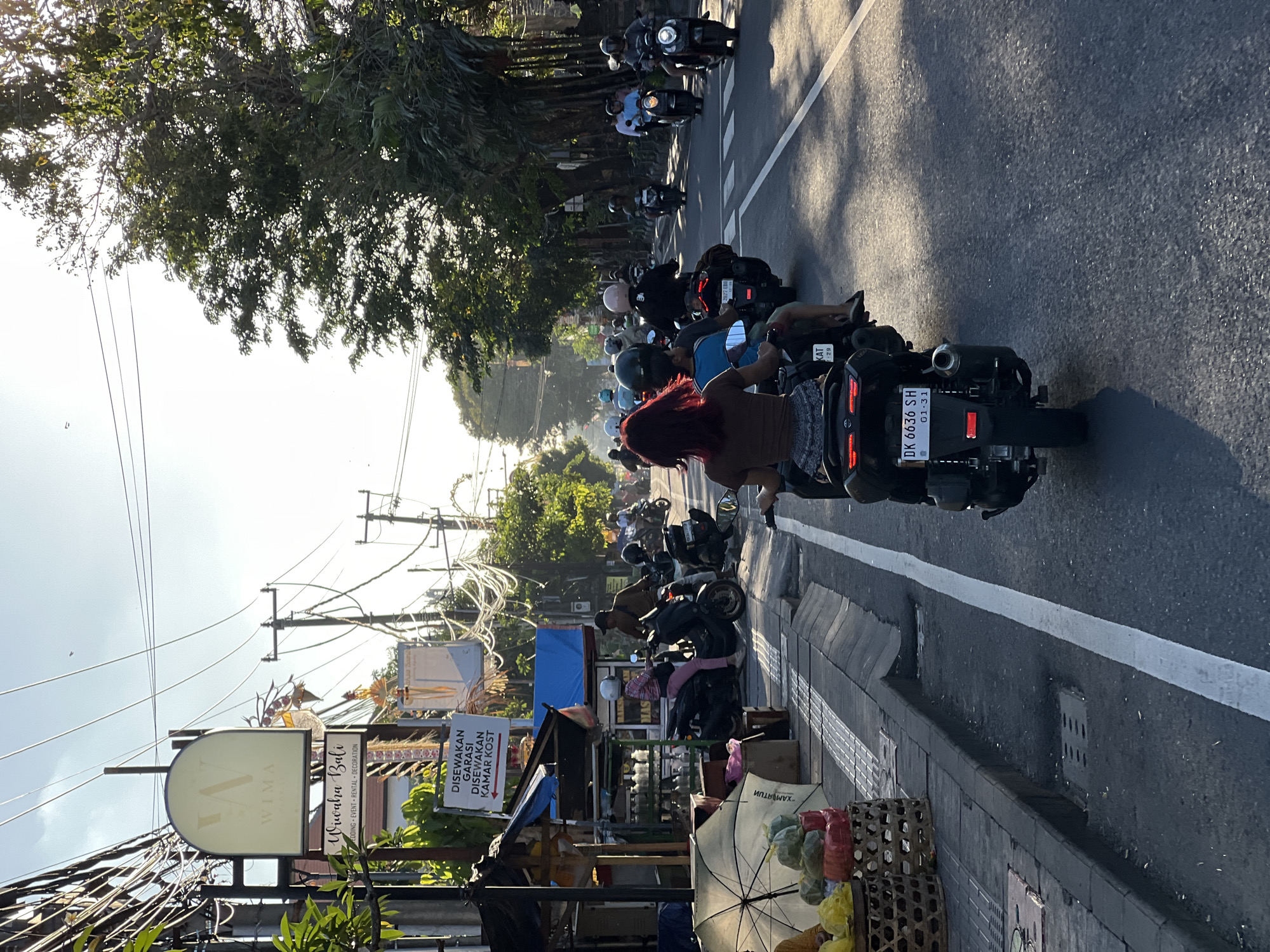 Motorcycle traffic flows through Denpasar streets at golden hour
