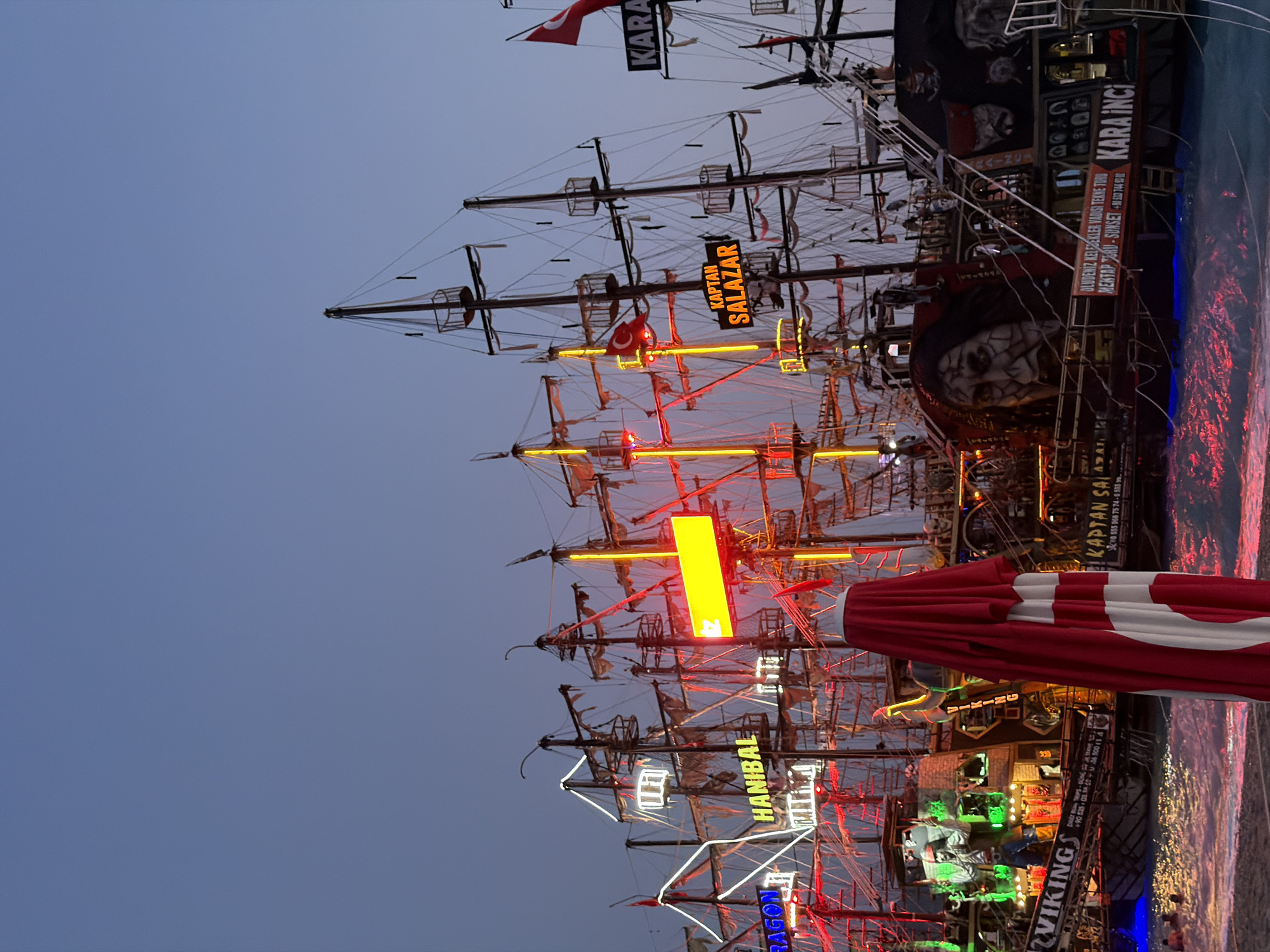 Neon-lit pirate boats line Fethiye harbor at dusk