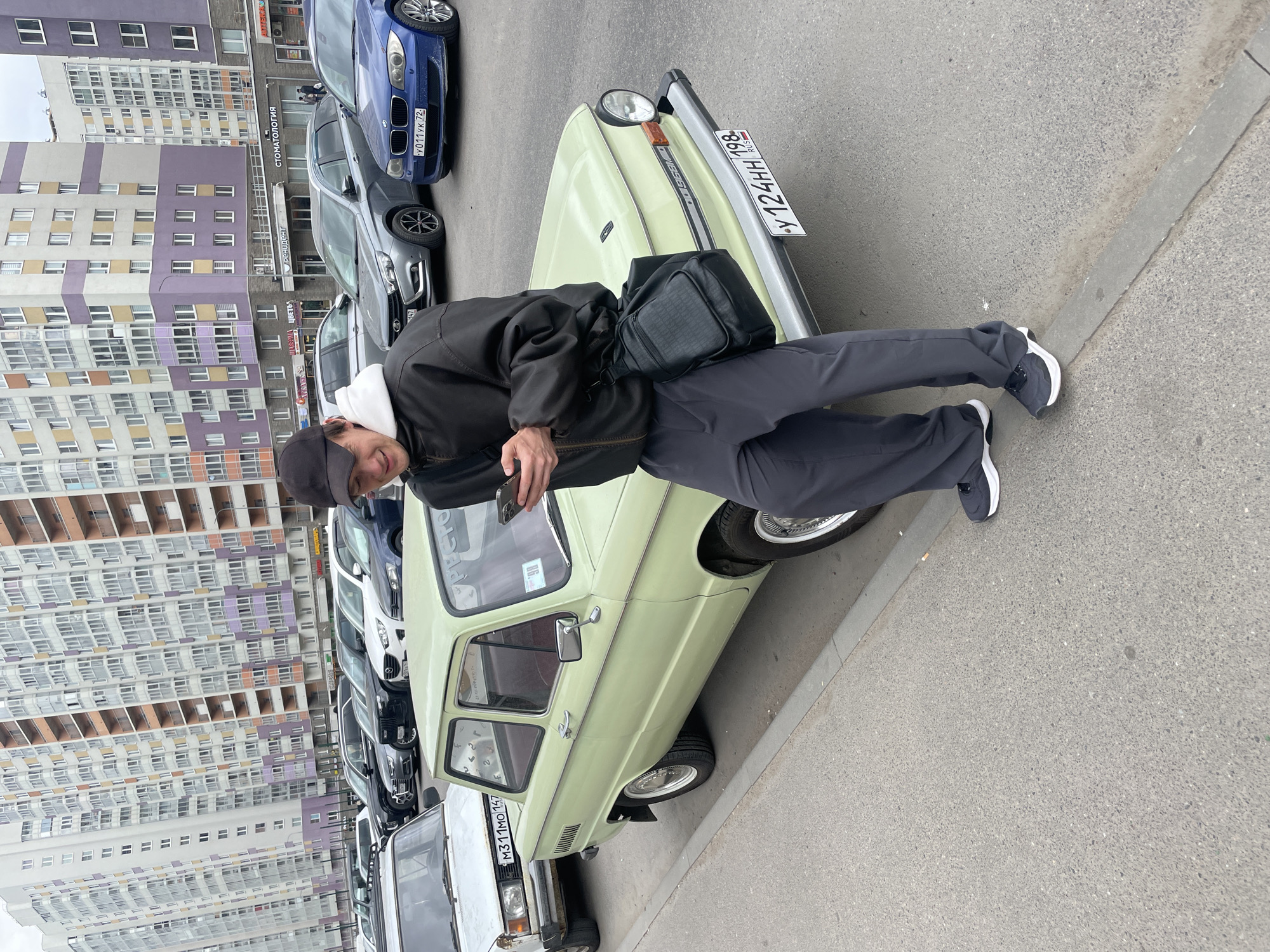 Man poses with vintage Soviet car on Russian street