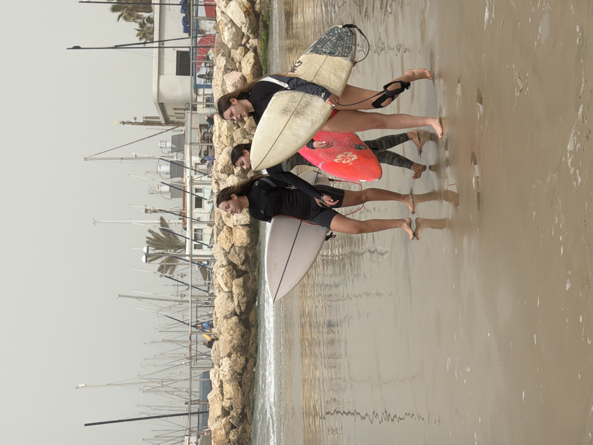 Three women carry surfboards on Tel Aviv beach