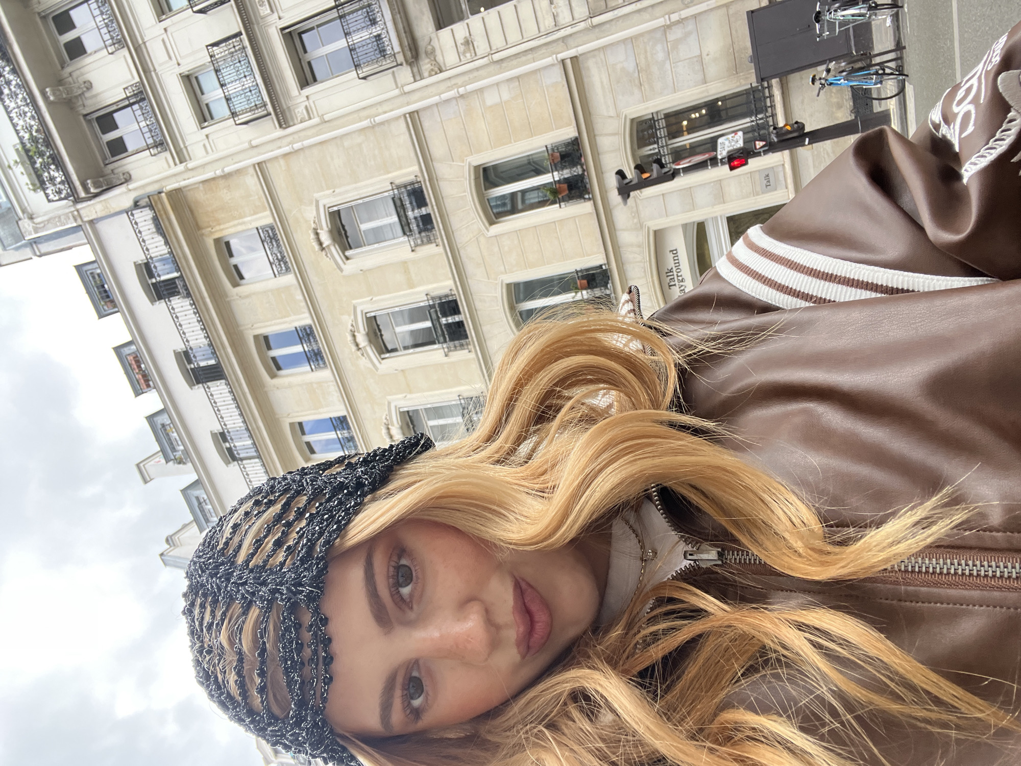 Woman in striped leather jacket photographed outside Paris building
