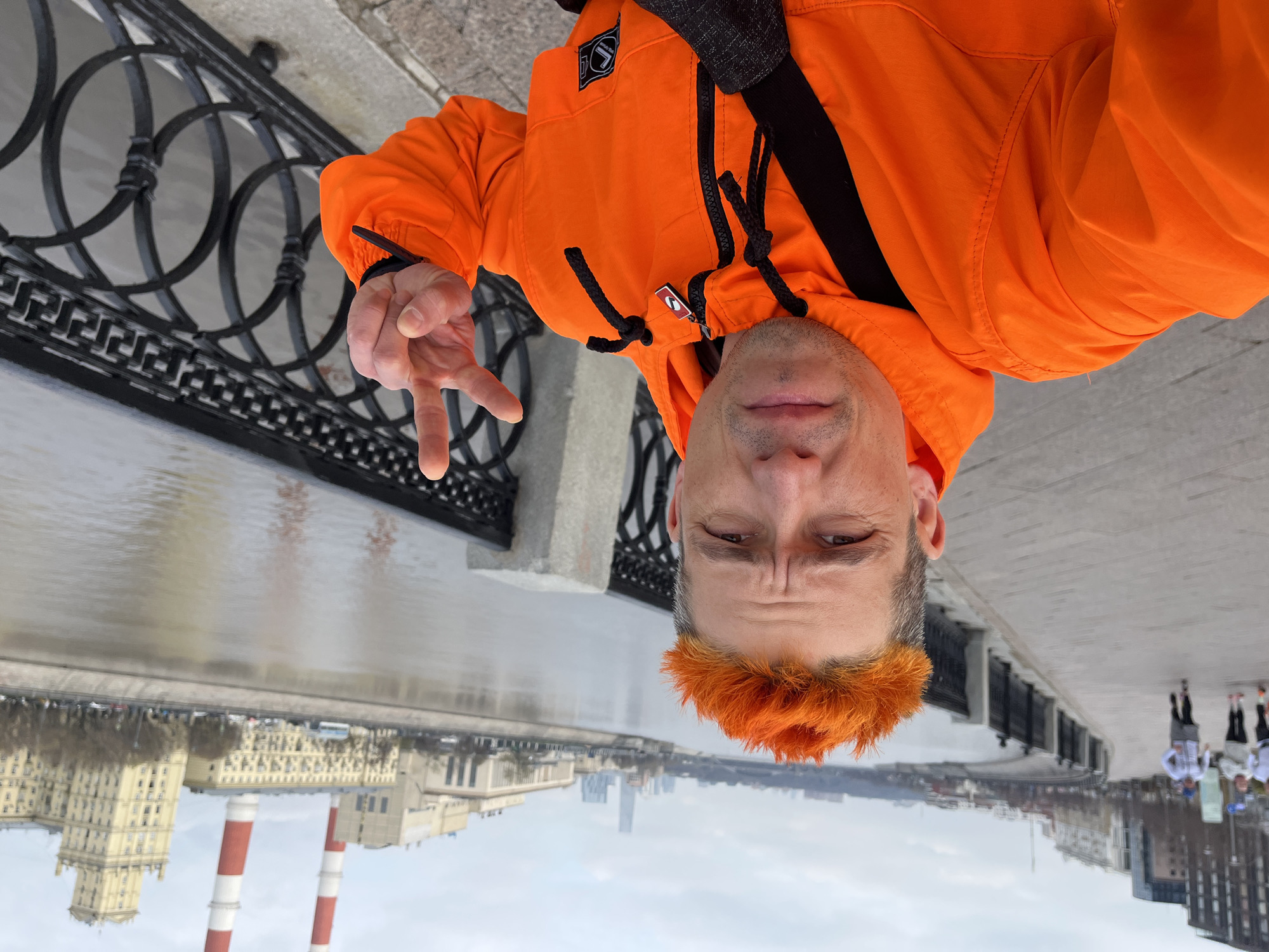 Man takes selfie on Moscow bridge while others walk riverside