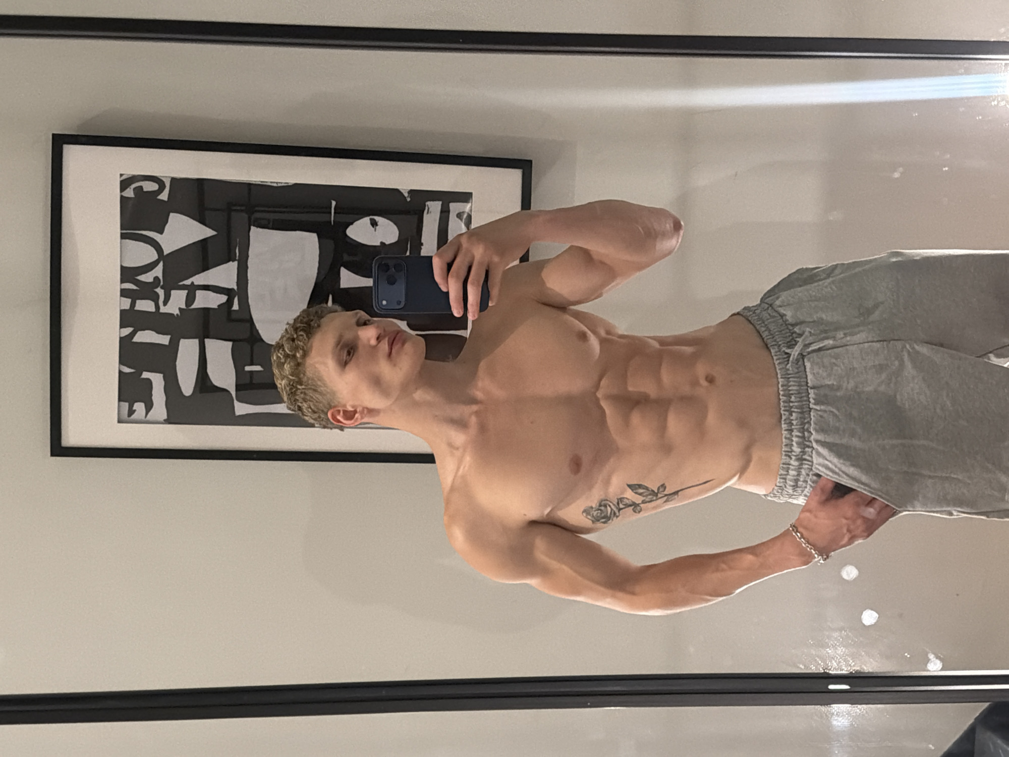 Mirror selfie showing a rose tattoo, London home interior.