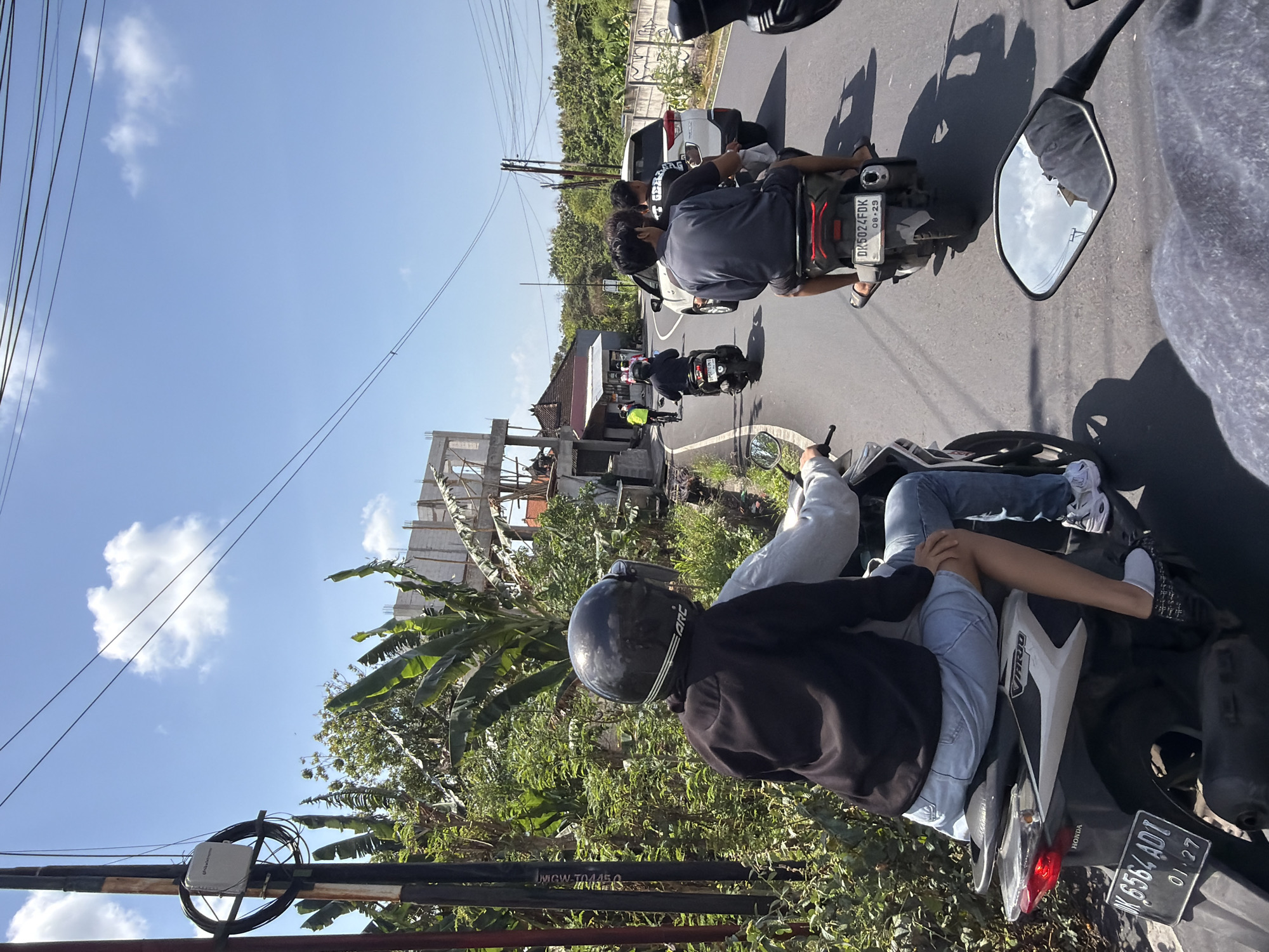 Motorcycles and cyclists navigate sunny Kuta Selatan streets