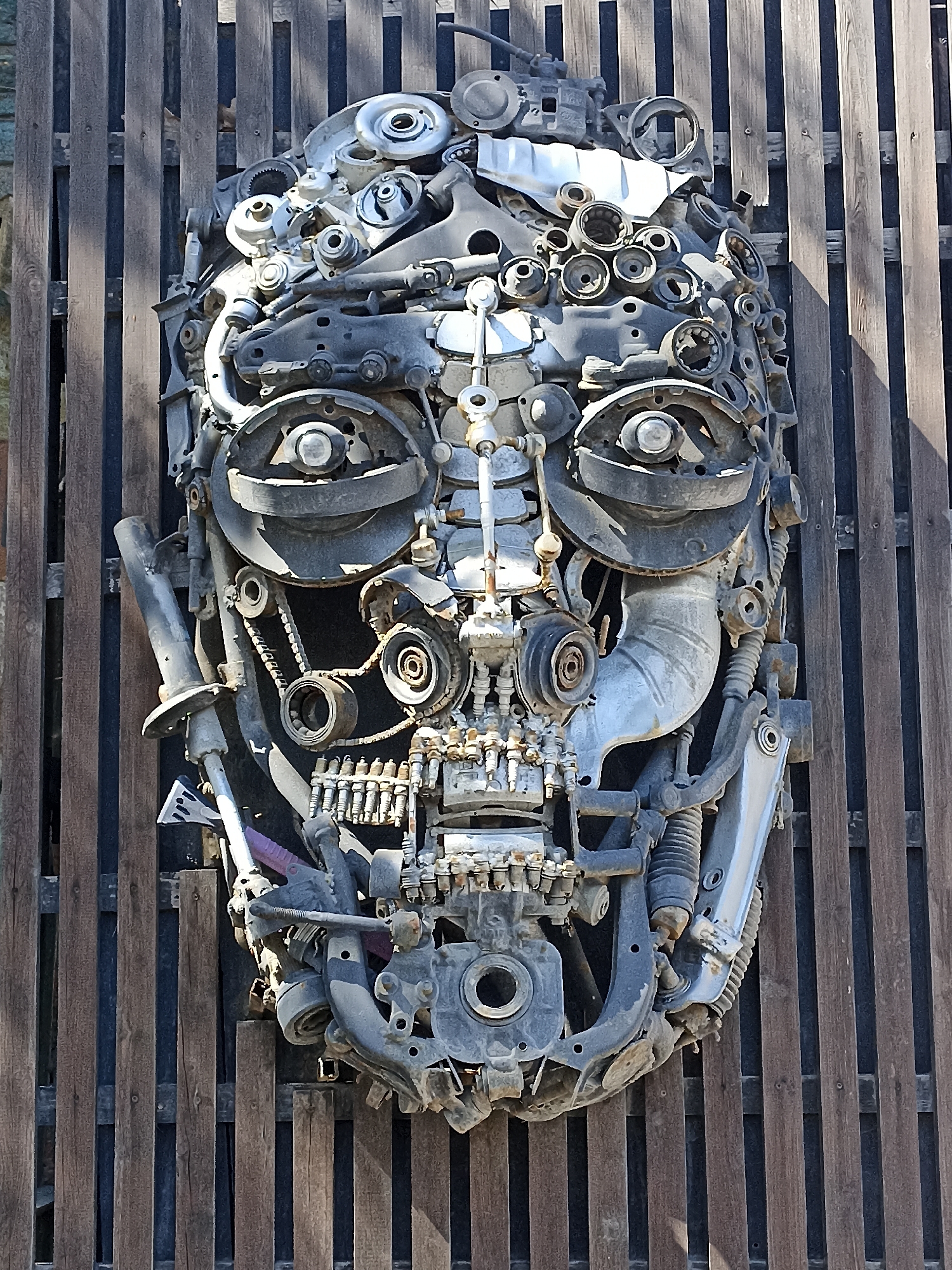 Car part face sculpture mounted on a fence in Novosibirsk