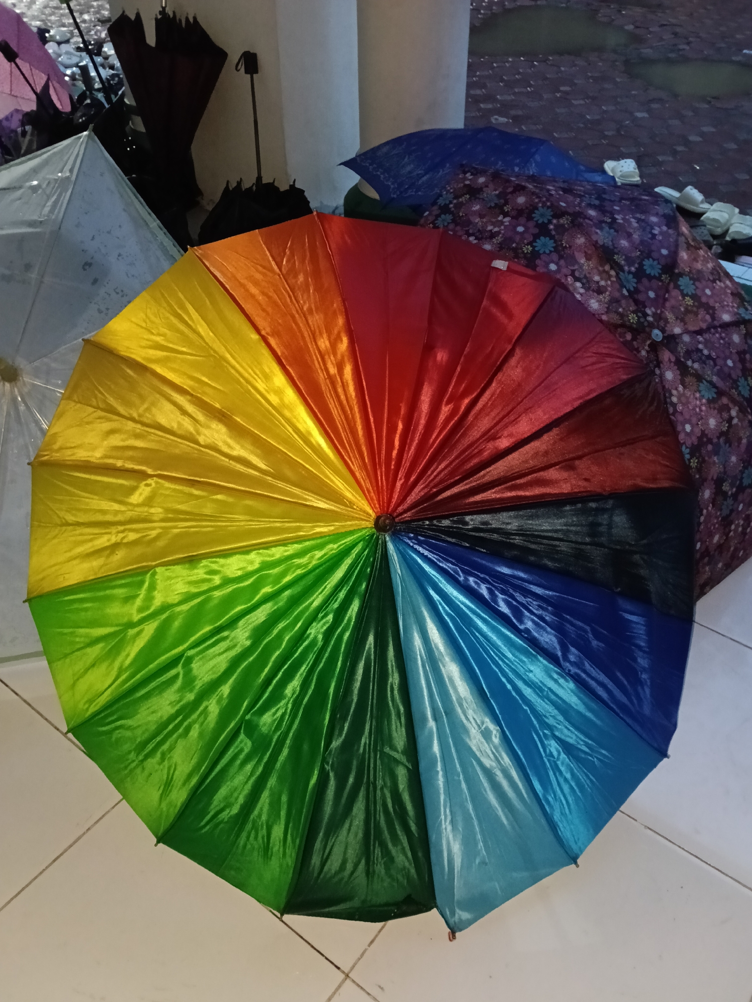 Rainbow umbrella spotted on tiled surface in Lhokseumawe
