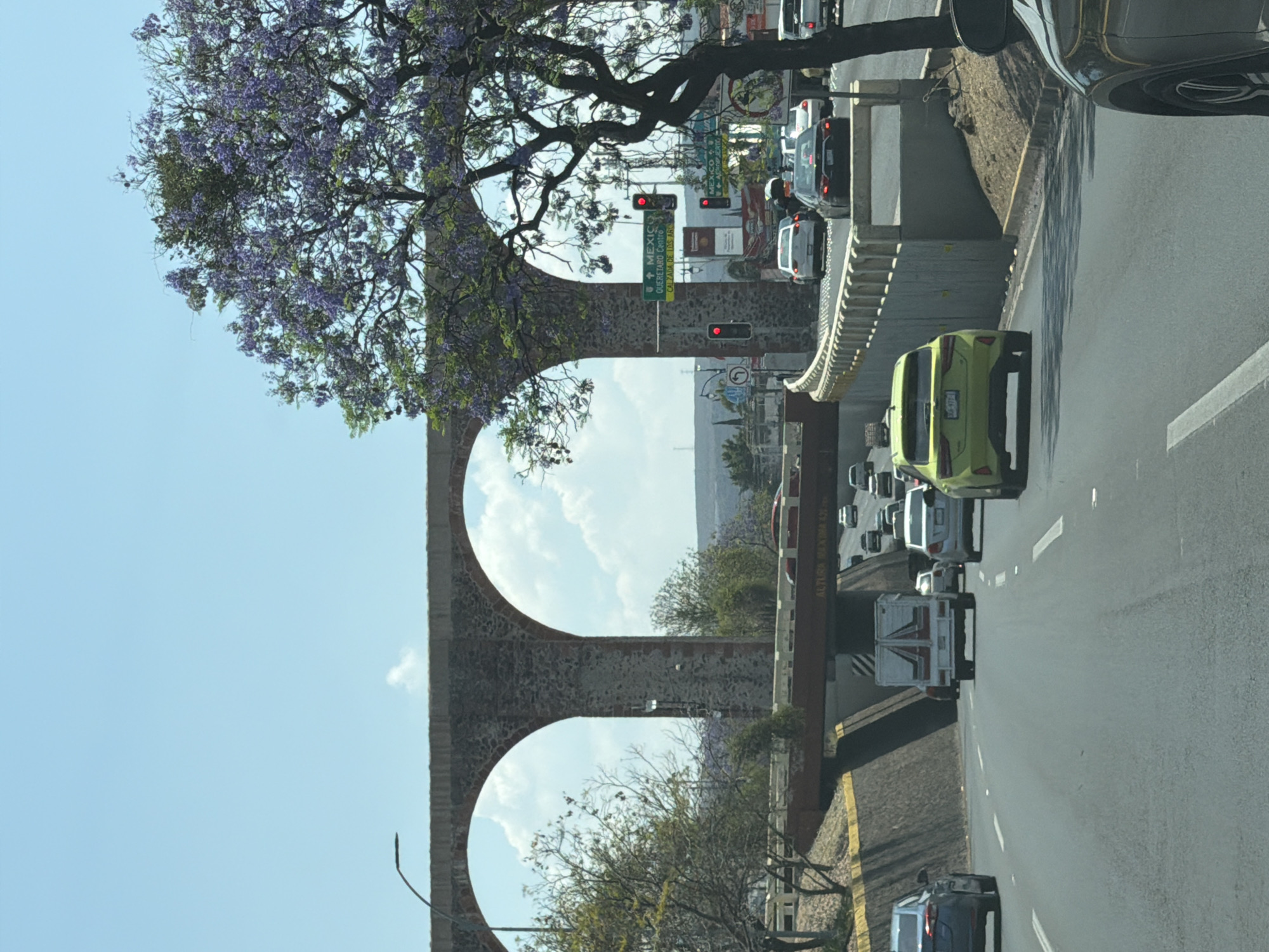 Stone aqueduct spans urban traffic scene