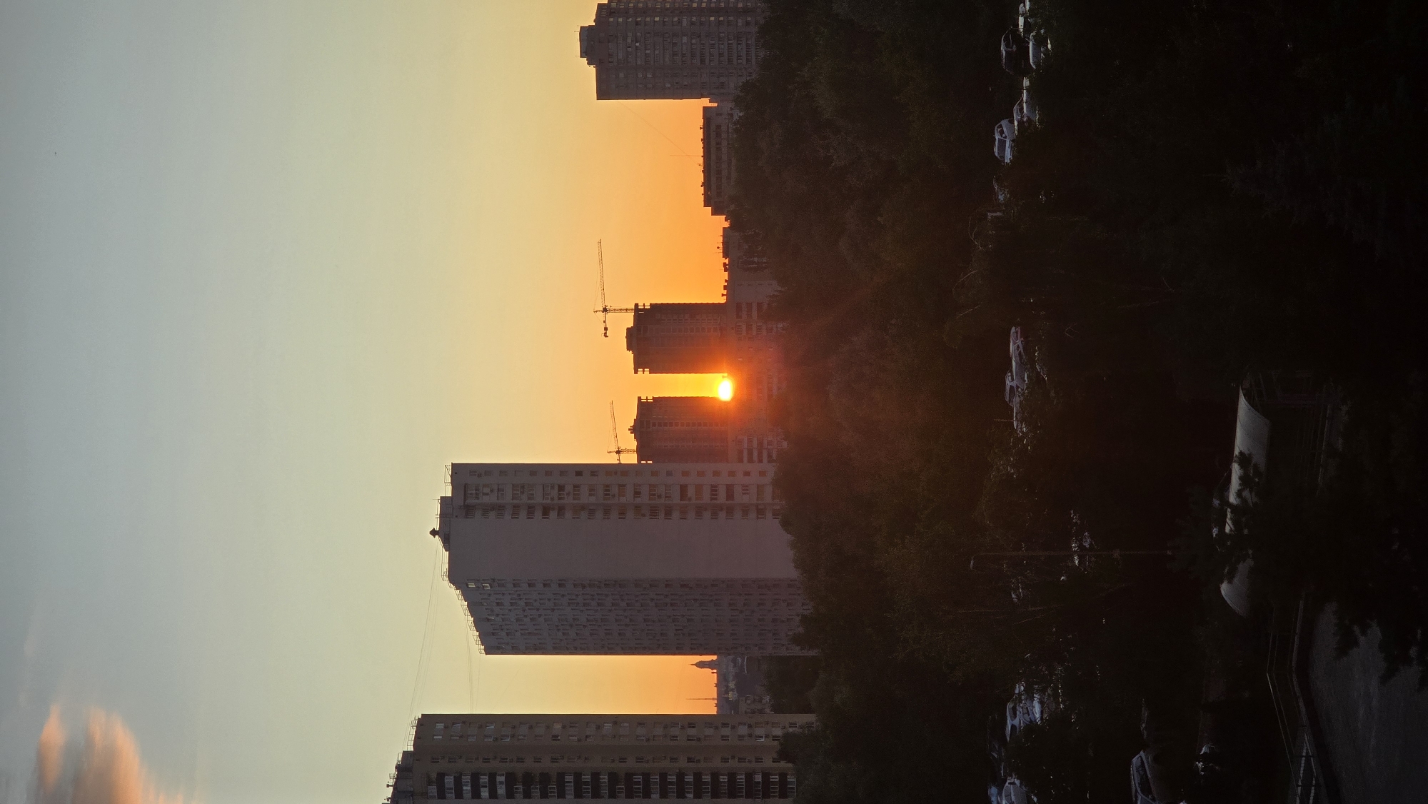 Kyiv skyline at sunset, high-rises cutting through orange sky