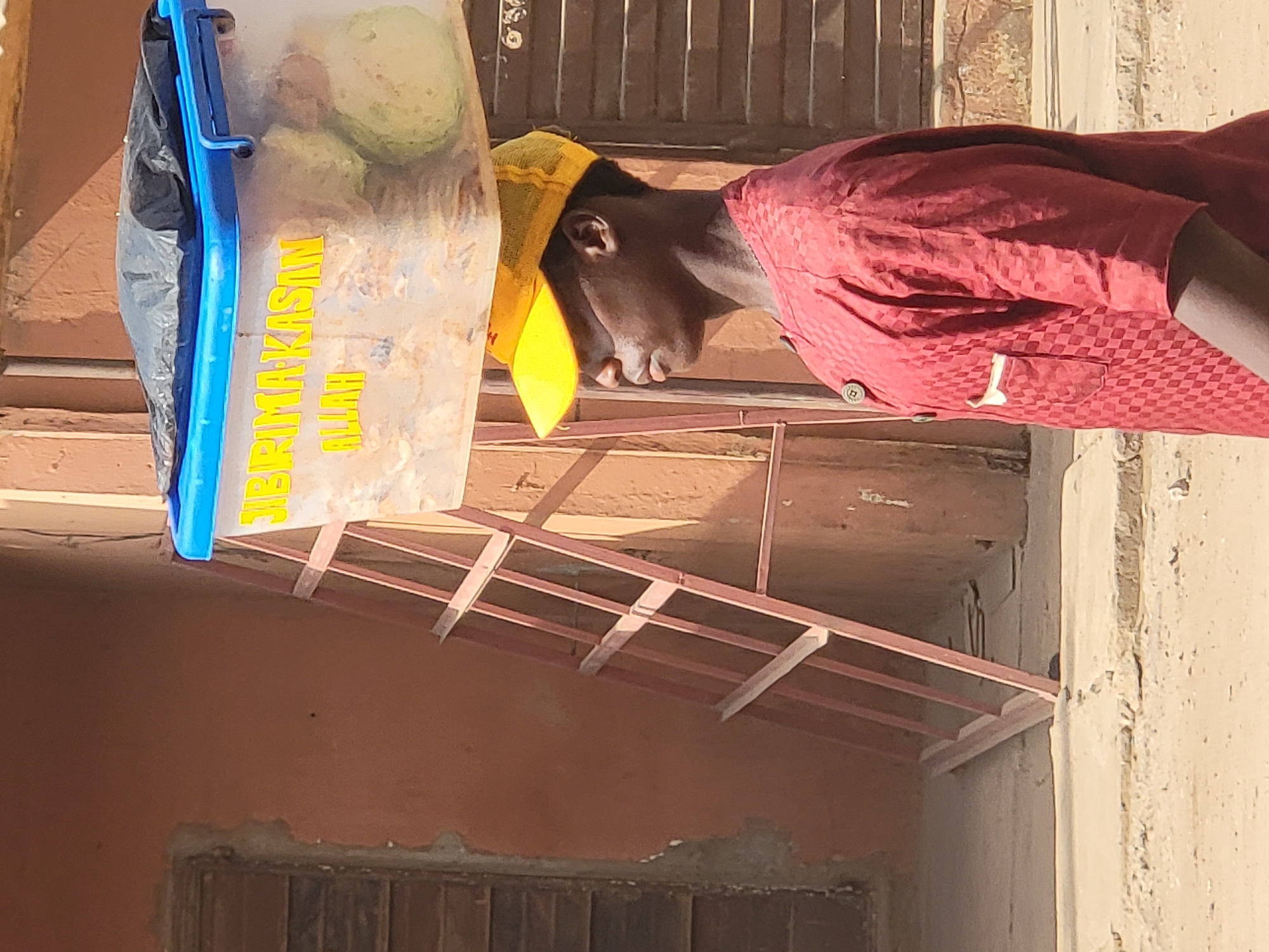 Man carries labeled food waste container in Maiburiji, Nigeria