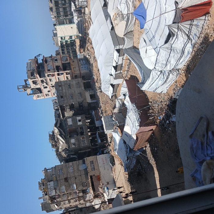 Large displacement camps documented amid damaged Gaza City buildings