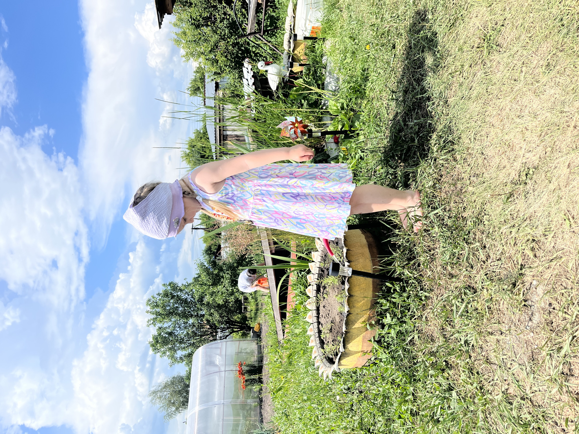 Girl plays with toys, pets in Russian village yard