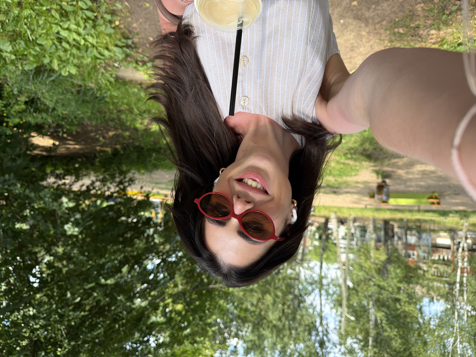 Selfie session outdoors, striped dress, sunglasses, drink in hand