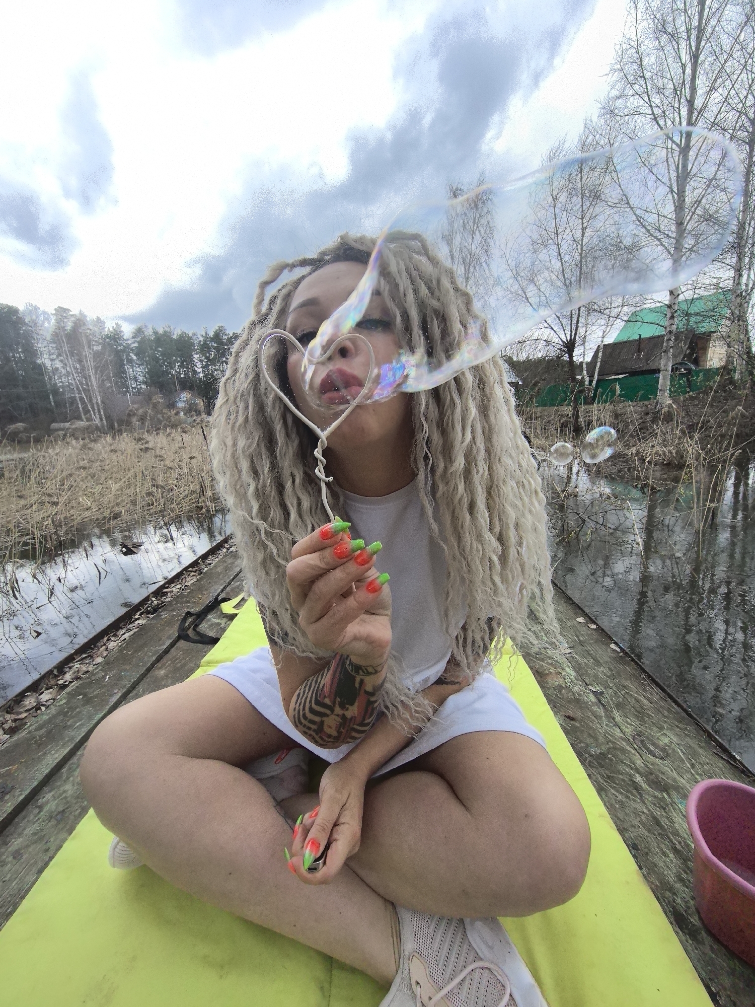 Woman blows bubbles on waterside pier in Noviy, Russia
