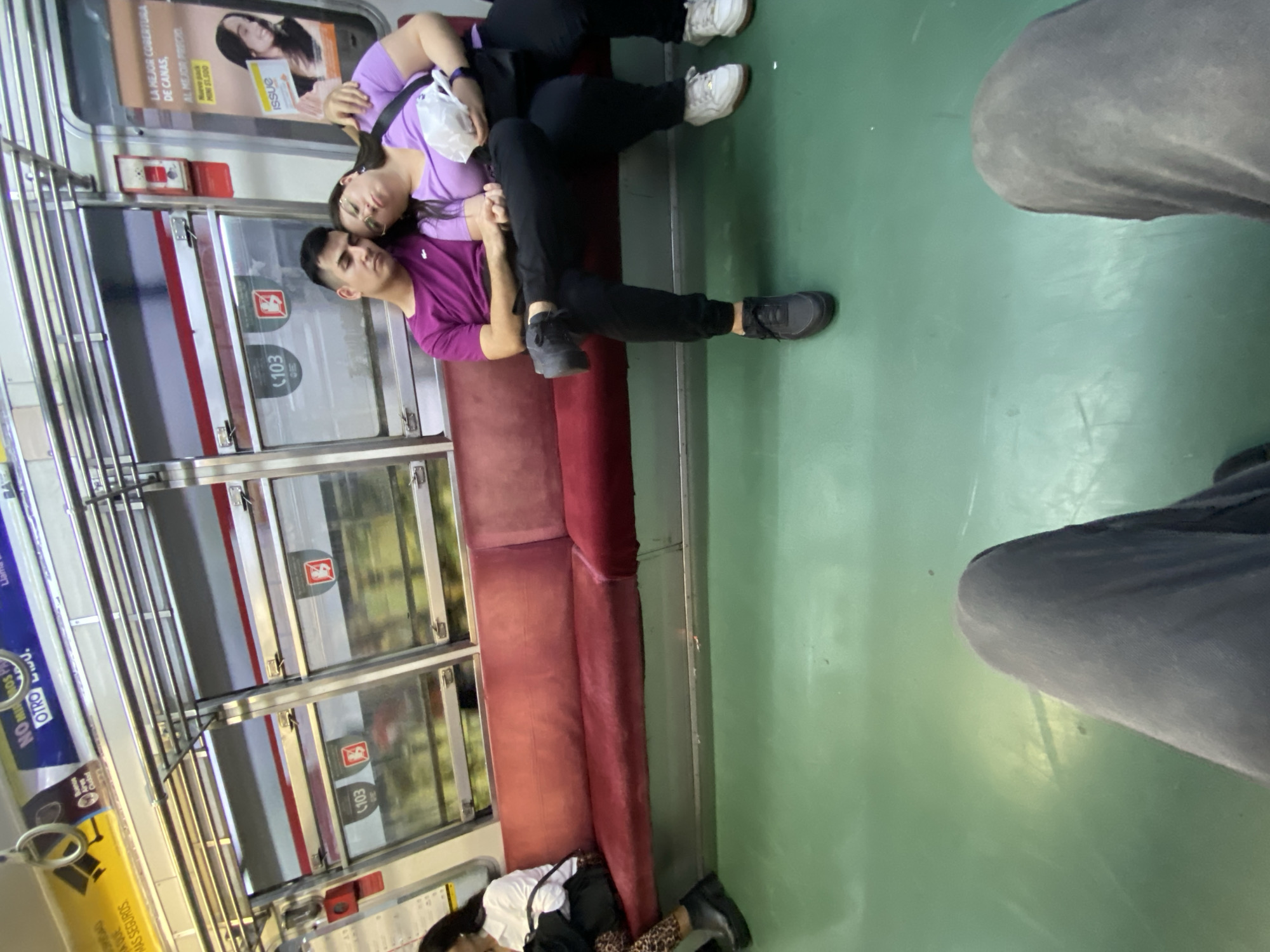 Couple lies across subway seats in Buenos Aires transit car