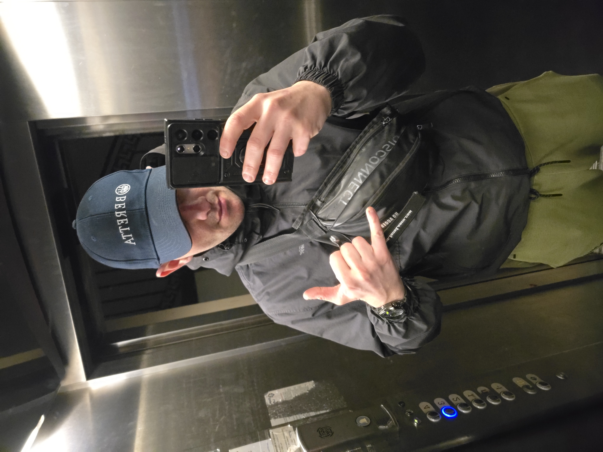 Man takes selfie in Sofia elevator wearing branded clothing