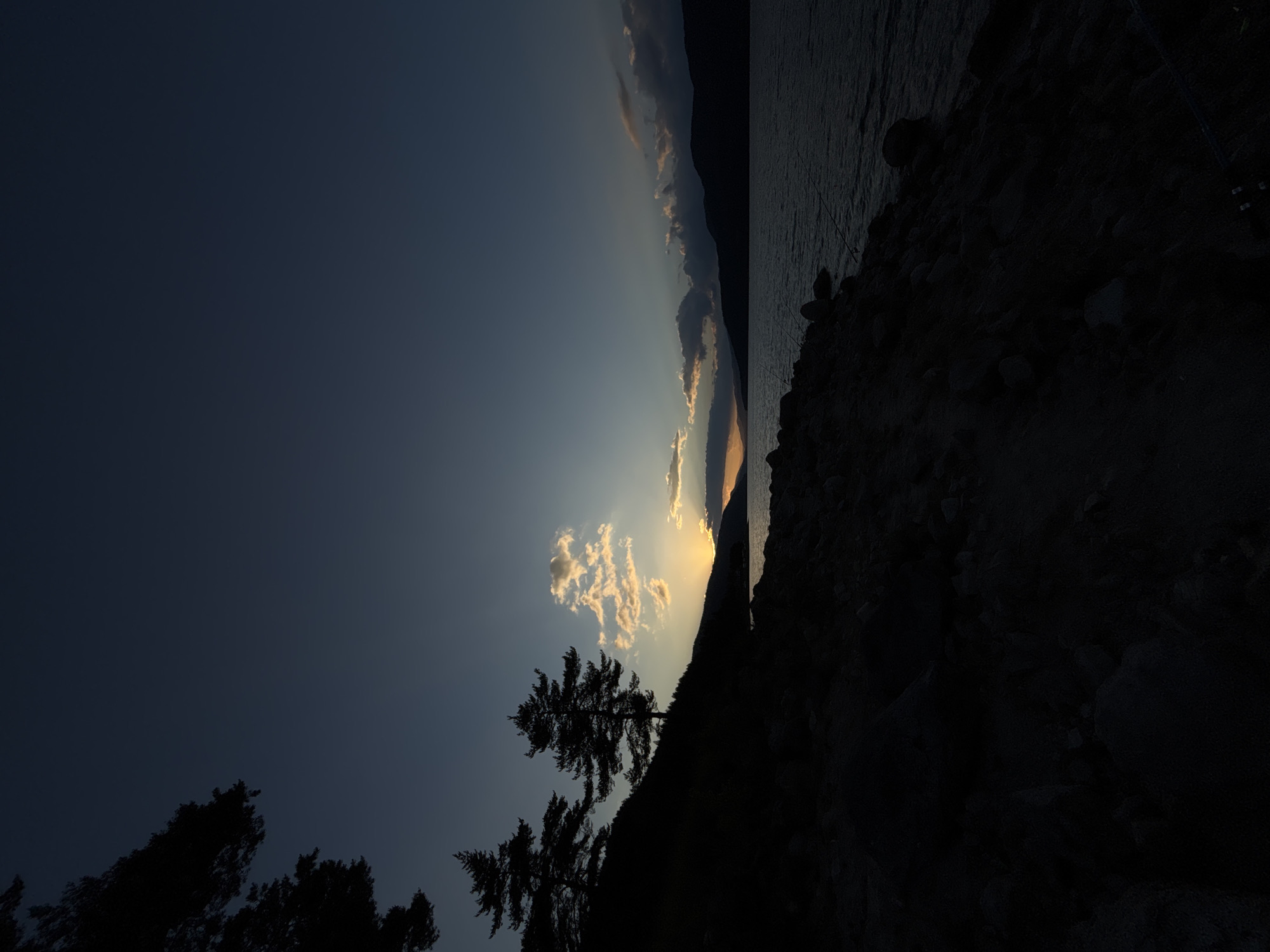 Sunset over a mountain lake, pine silhouettes and fading light