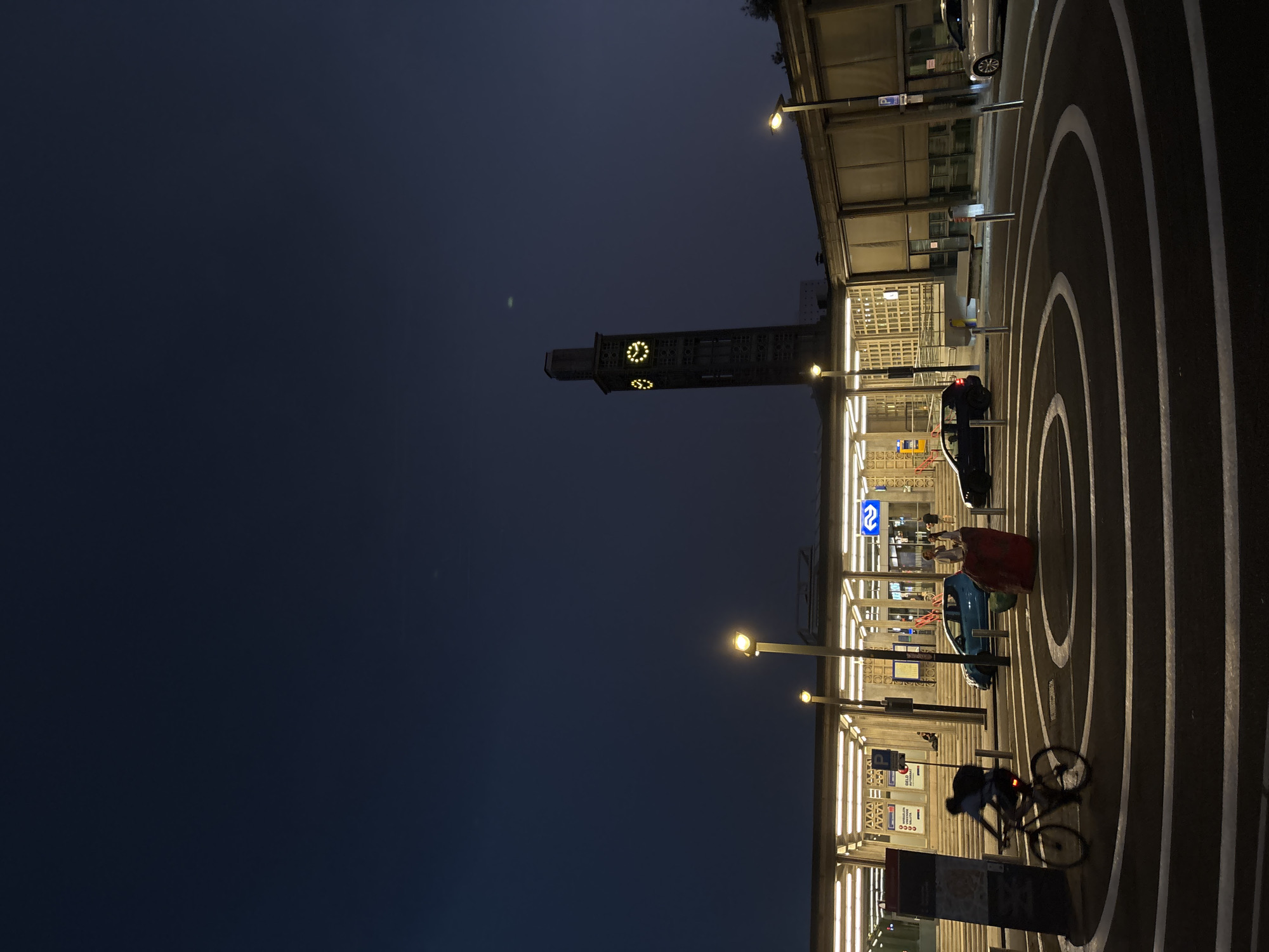 Cyclist passes Enschede Central Station at dusk