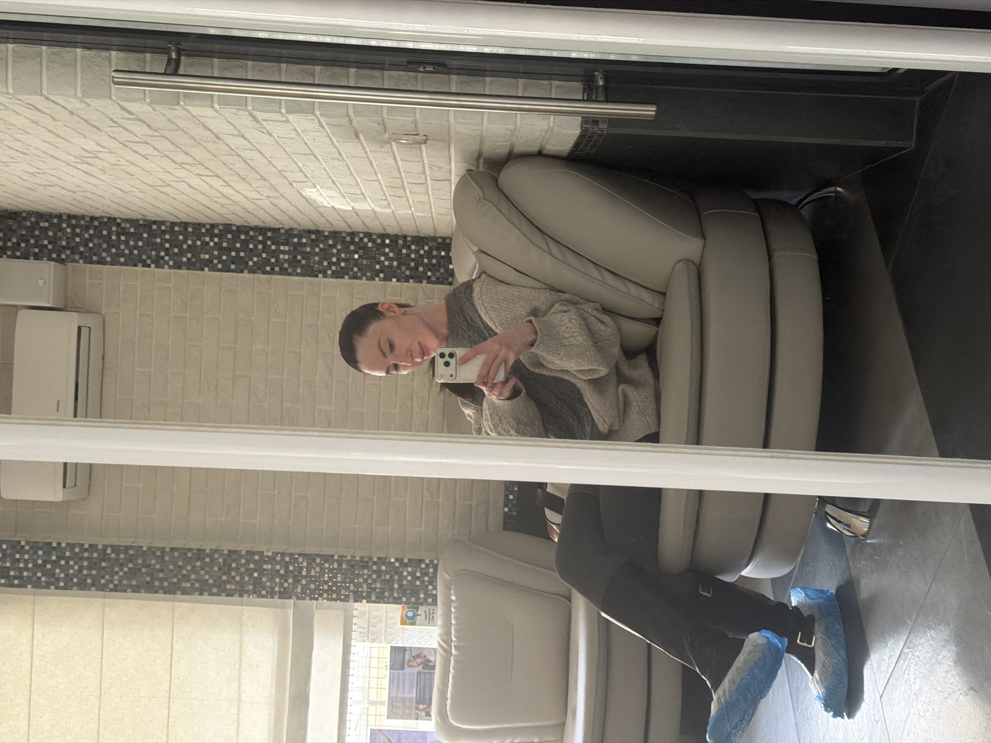 Woman takes selfie in chair, captured via mirror reflection