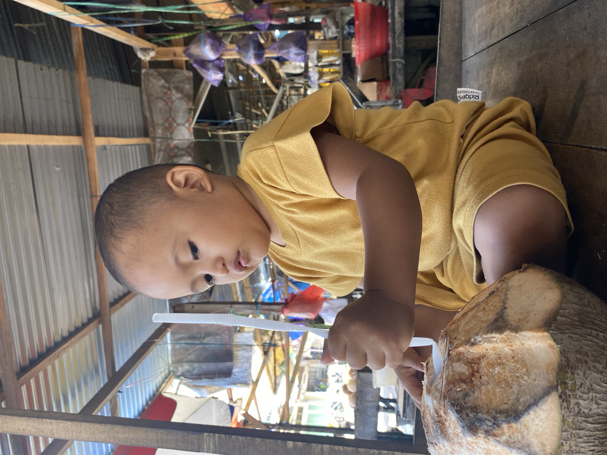 Toddler visits coconut market stall in Ta', Indonesia