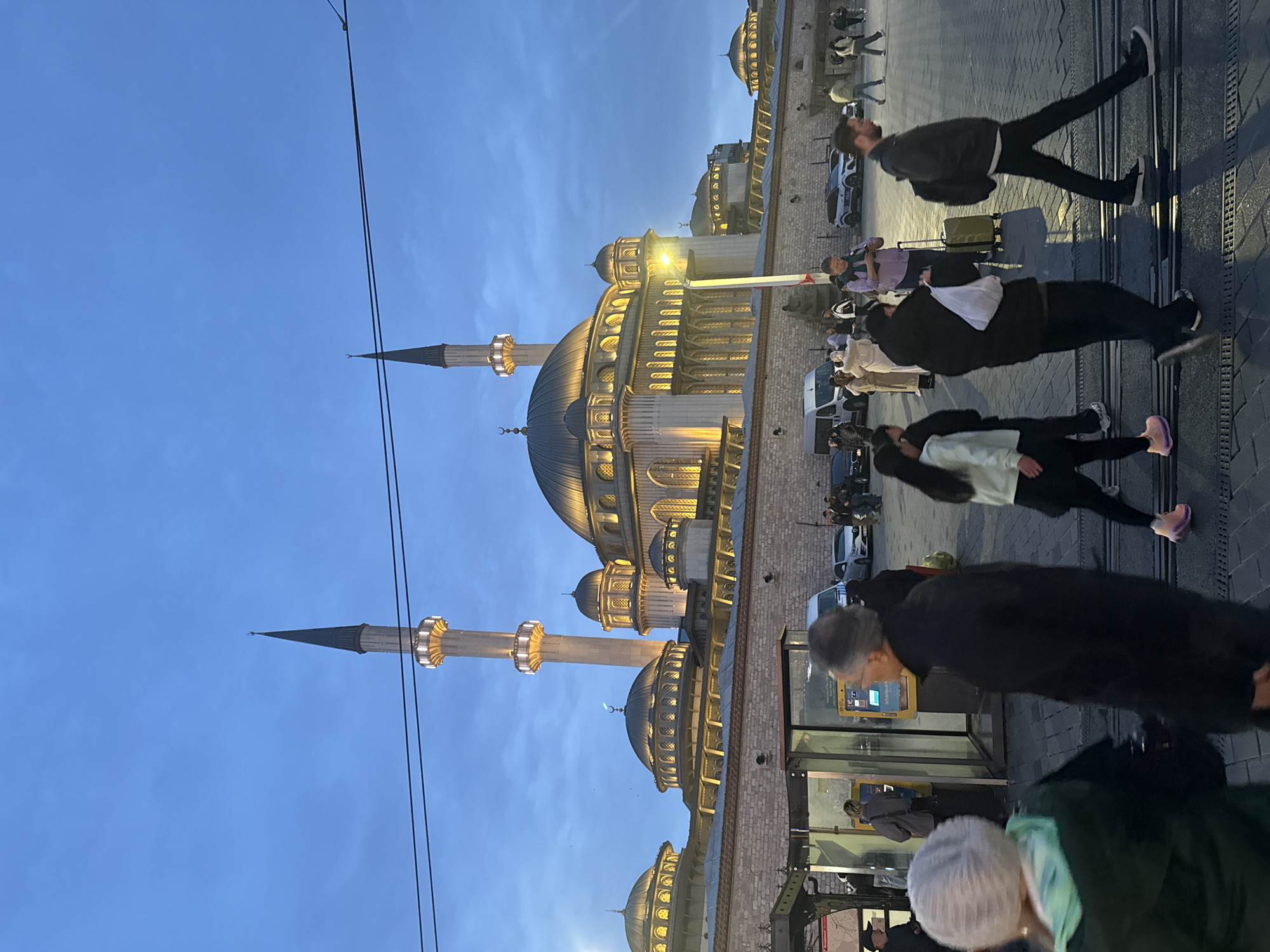 Evening pedestrians gather near illuminated mosques in Istanbul's Beyoğlu