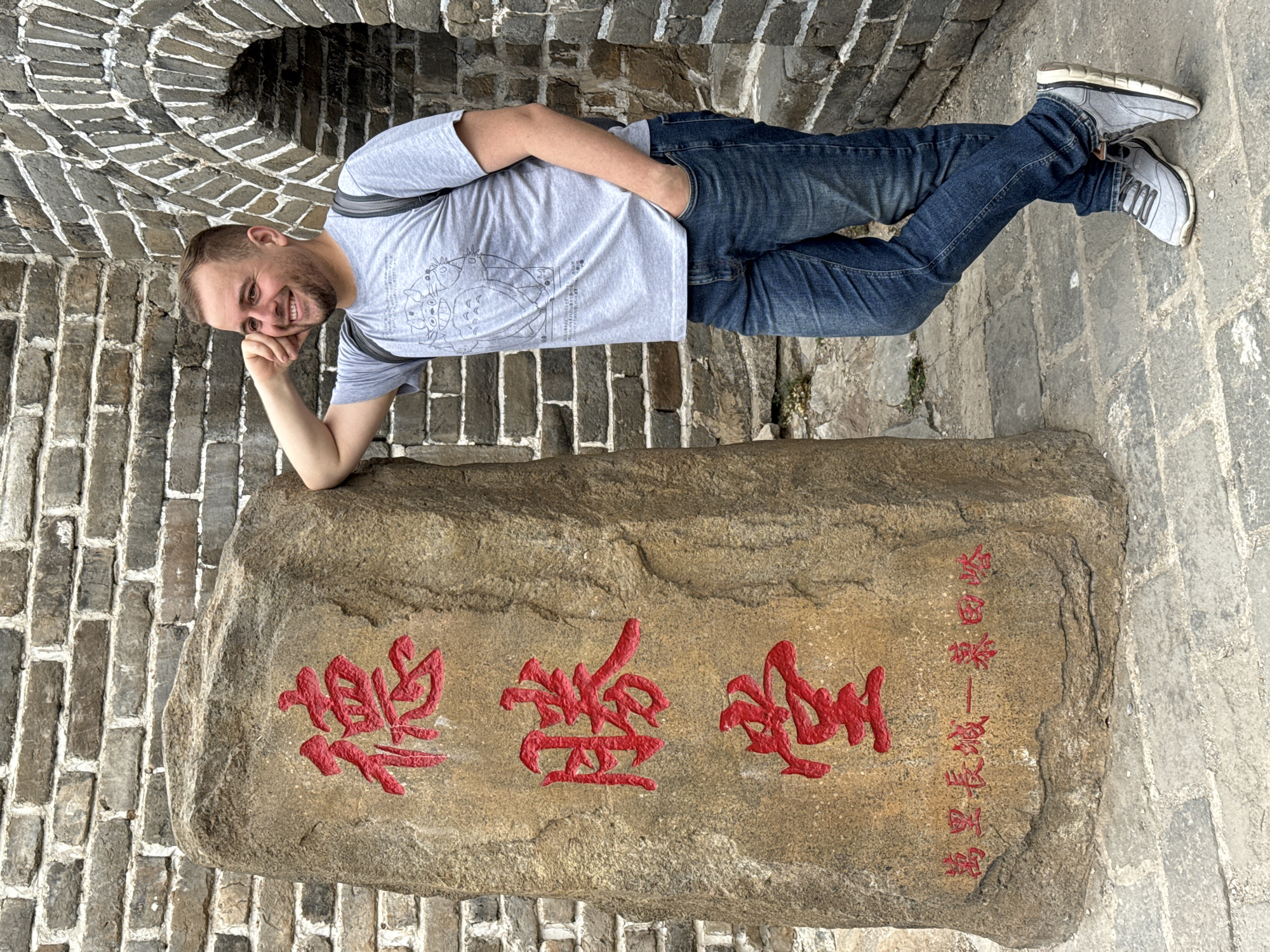 Visitor rests at Great Wall stone marker in Huairou